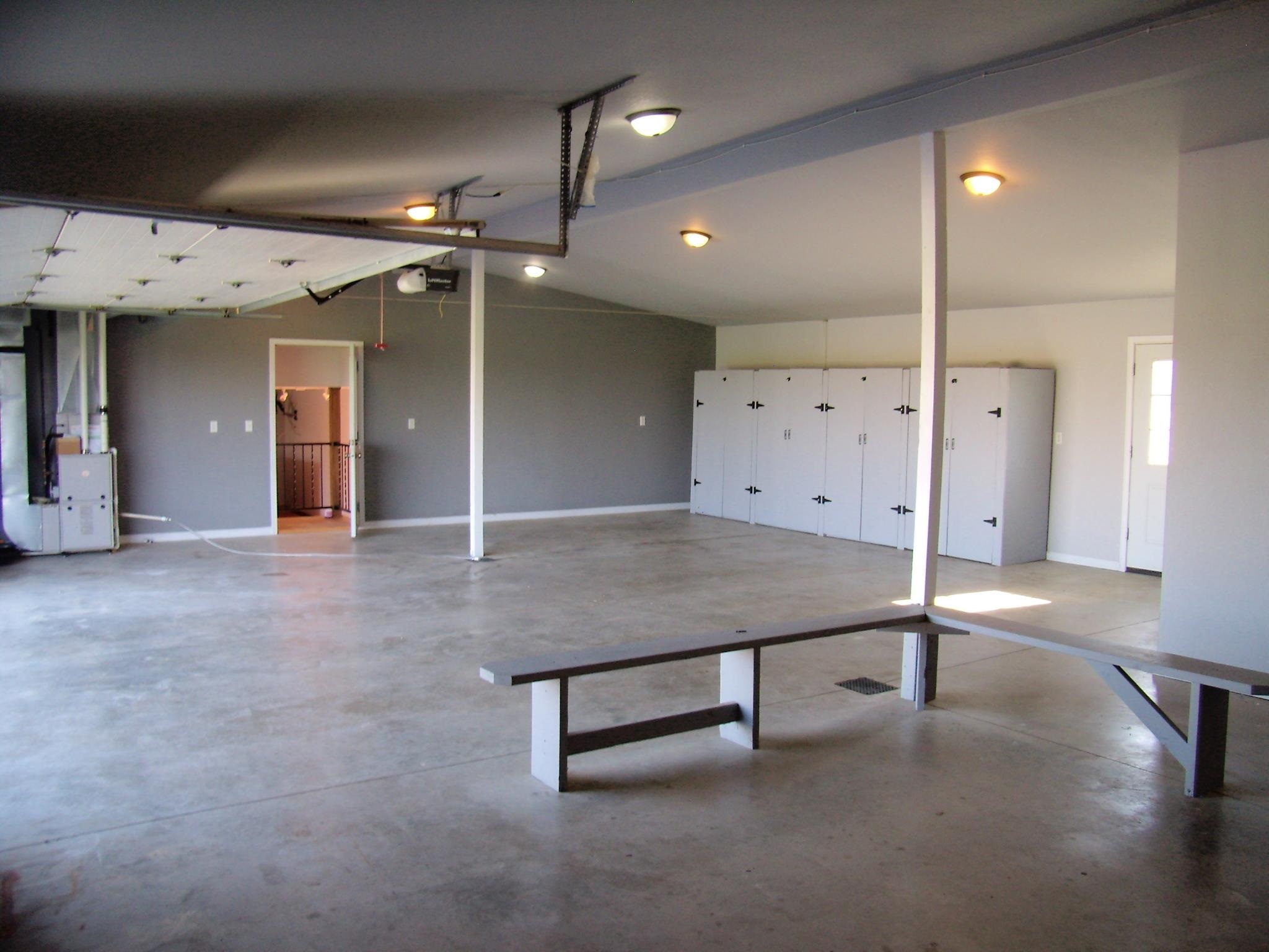 Spacious garage featuring concrete flooring, a series of built-in storage lockers, and overhead lighting