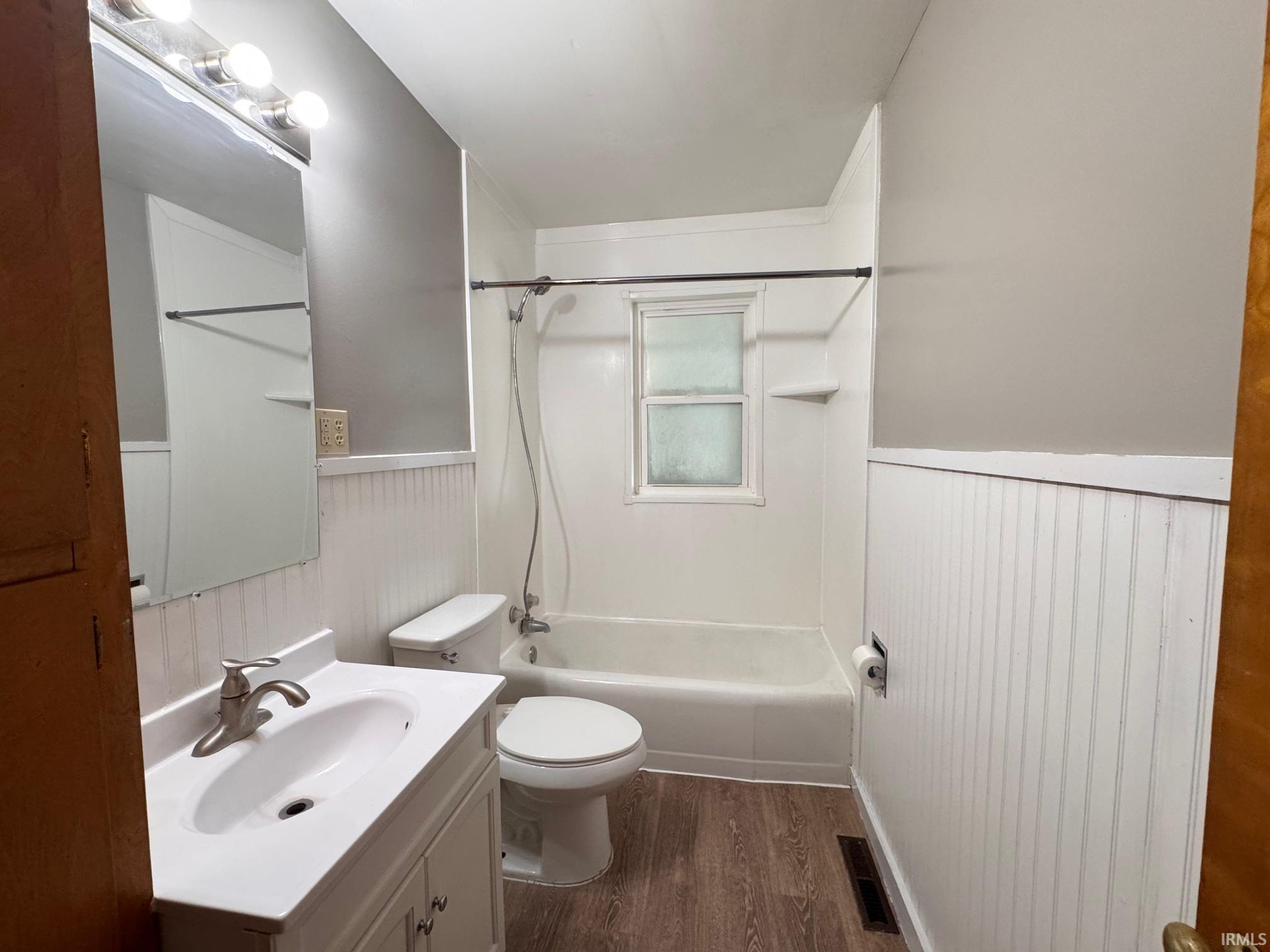 Bathroom featuring a white vanity with integrated sink, brushed nickel faucet, and overhead bar lighting