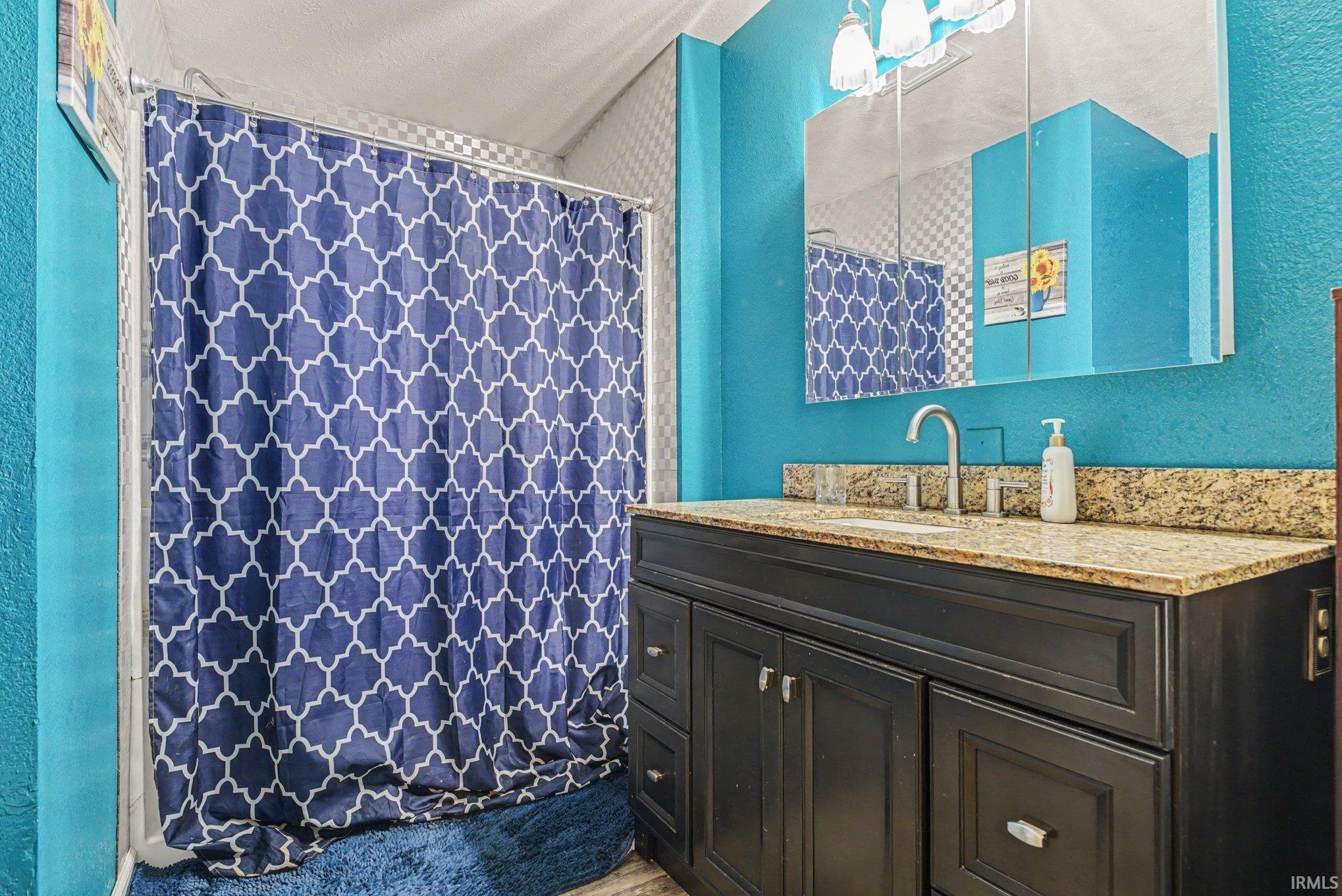 Bathroom featuring a dark wood vanity with a granite countertop, undermount sink, and brushed nickel faucet