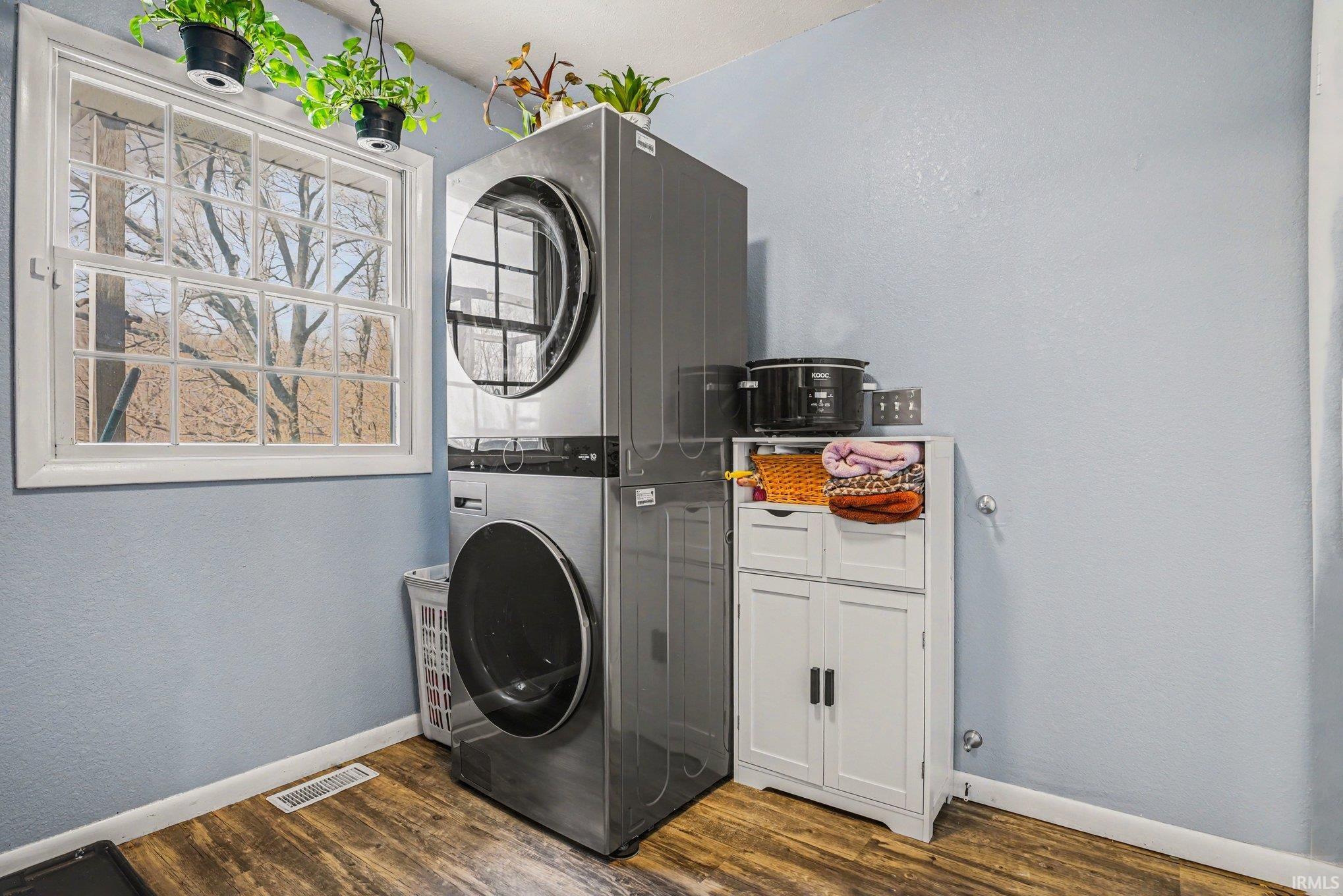 Utility room featuring wood-finish flooring, light blue wall paint, and a multi-pane window