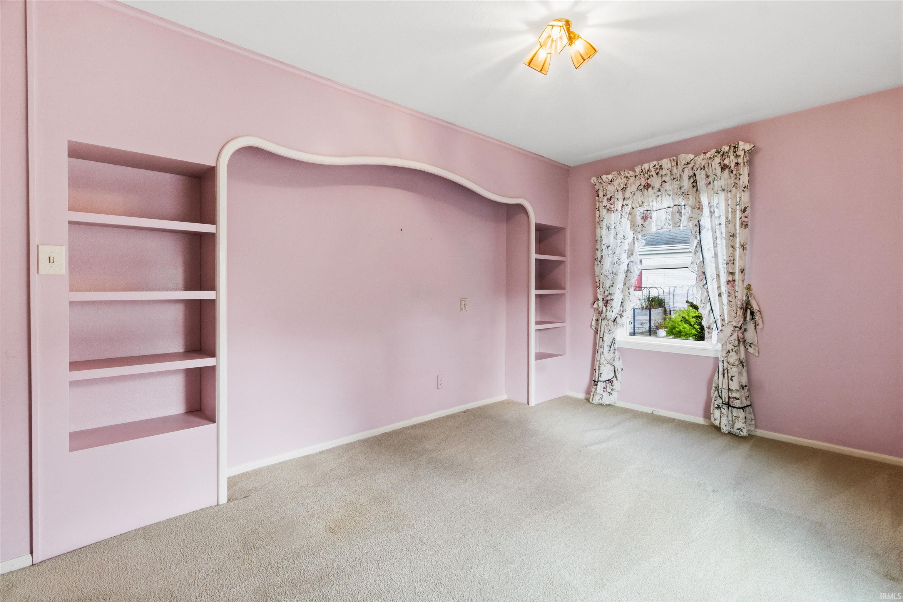 Recessed wall alcove with integrated shelving, accompanied by a window with white trim