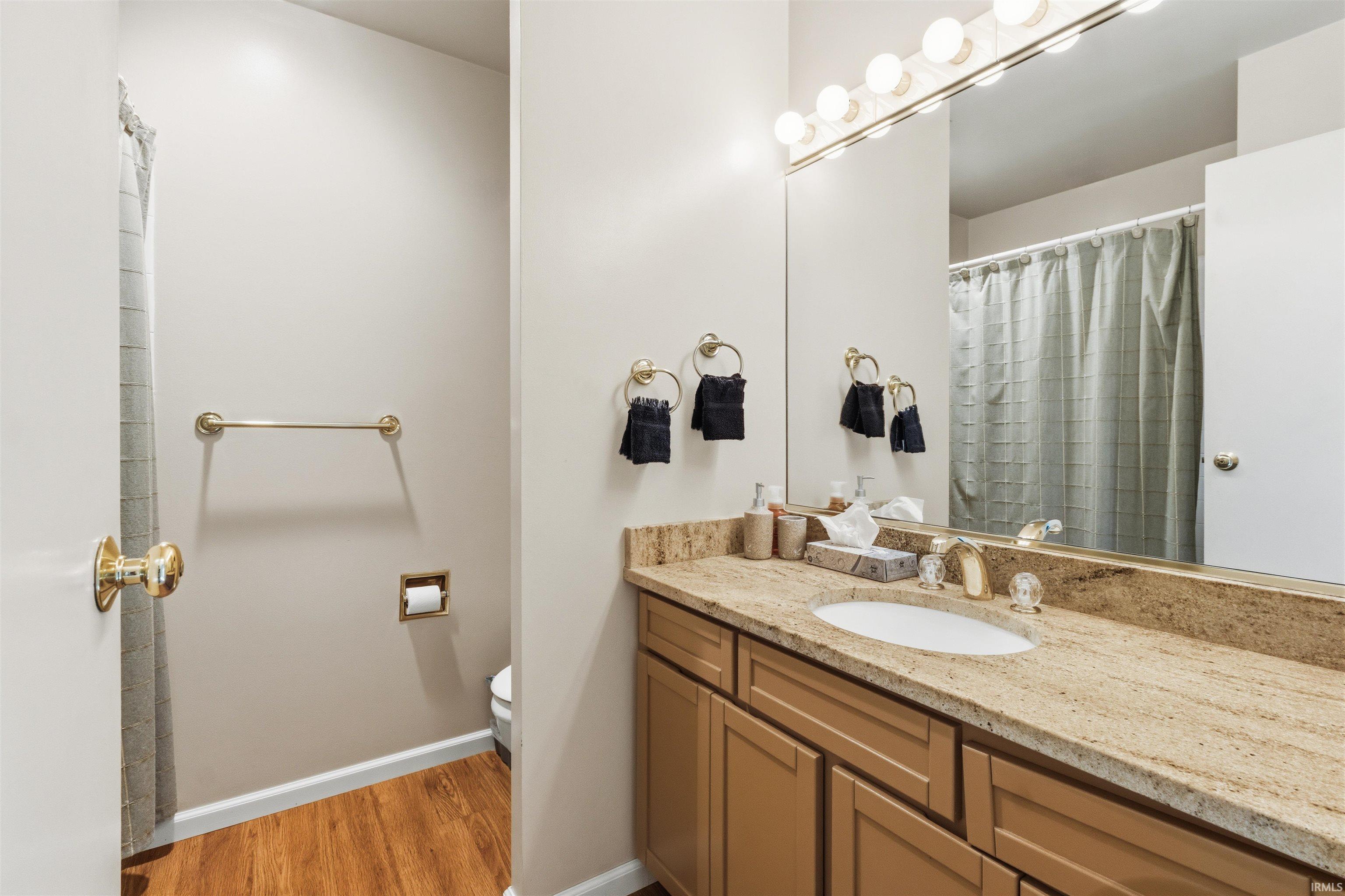 Bathroom featuring a vanity with a light-toned stone countertop, integrated sink, and wood-finish cabinetry