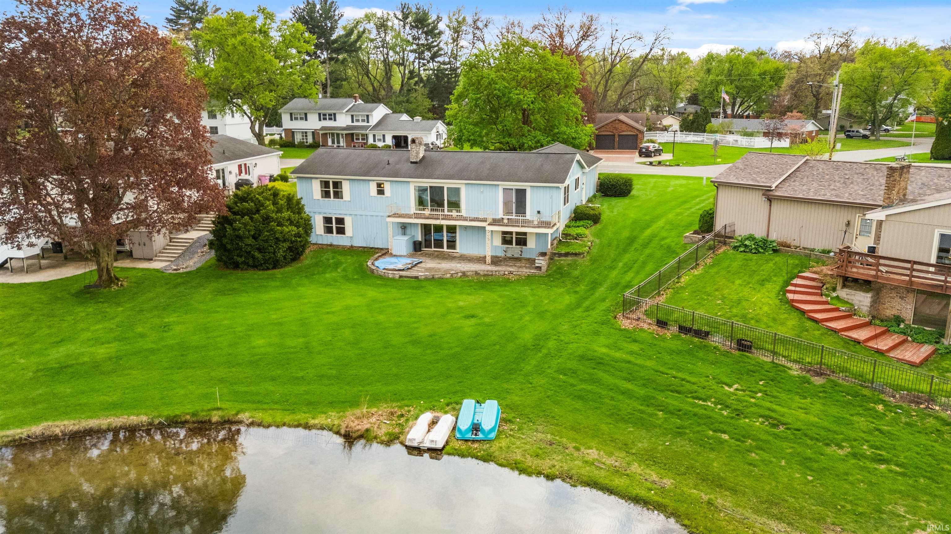 Expansive rear yard featuring a large pond, a multi-level deck, a patio, and a sloped lawn