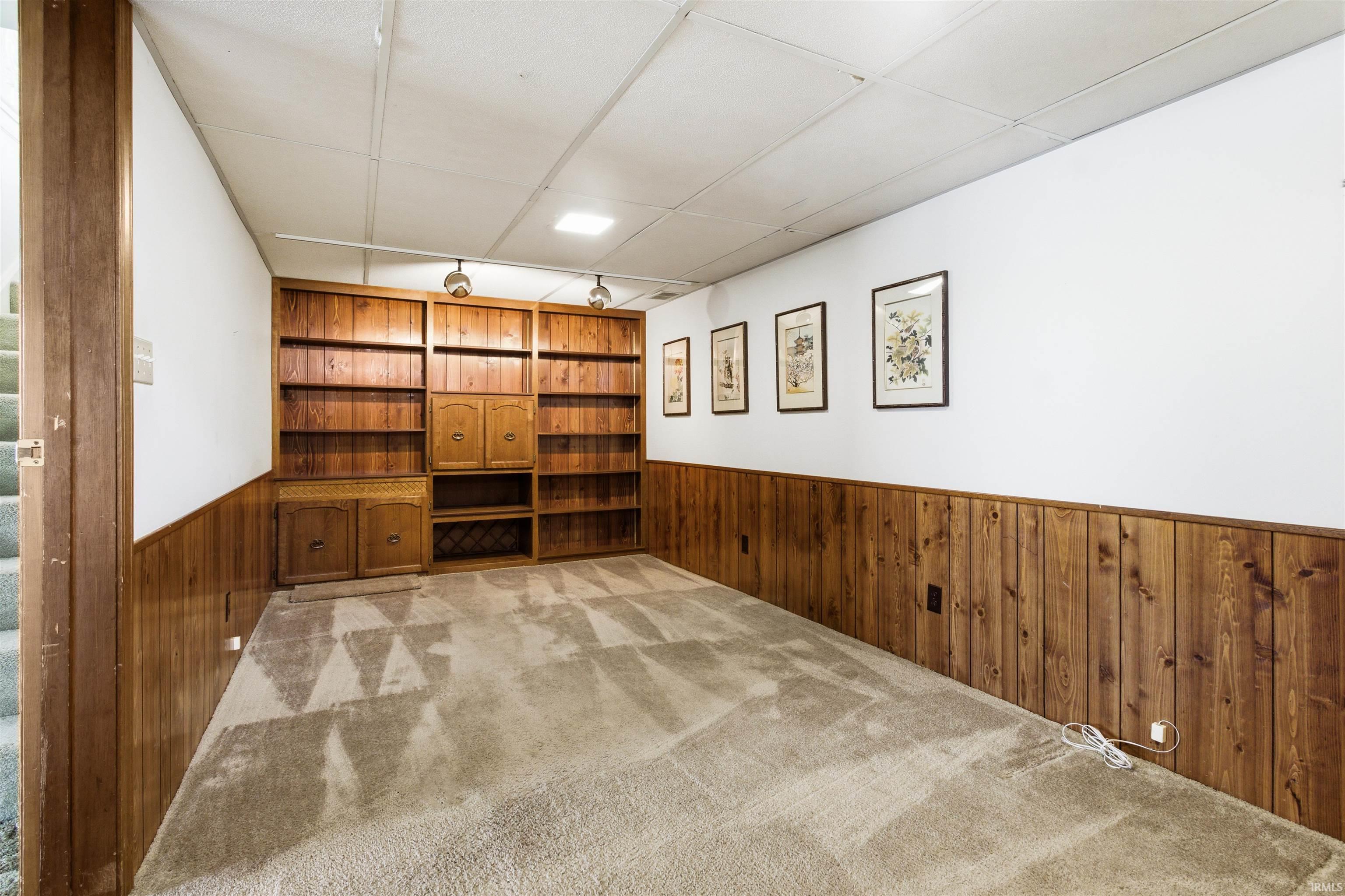Room featuring built-in wood shelving, wood paneling, recessed lighting, and carpet flooring