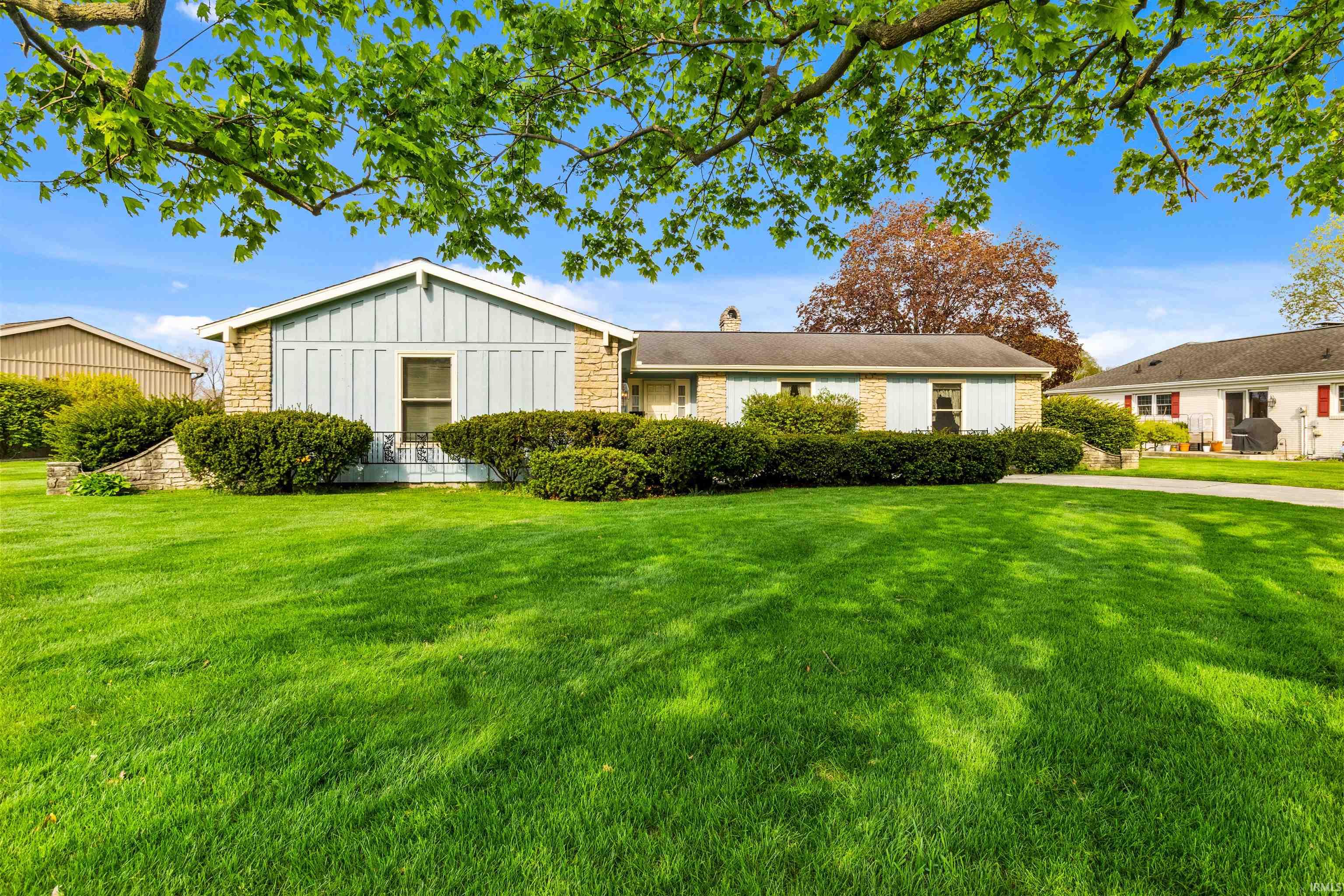 Expansive front lawn with mature trees and established perimeter landscaping