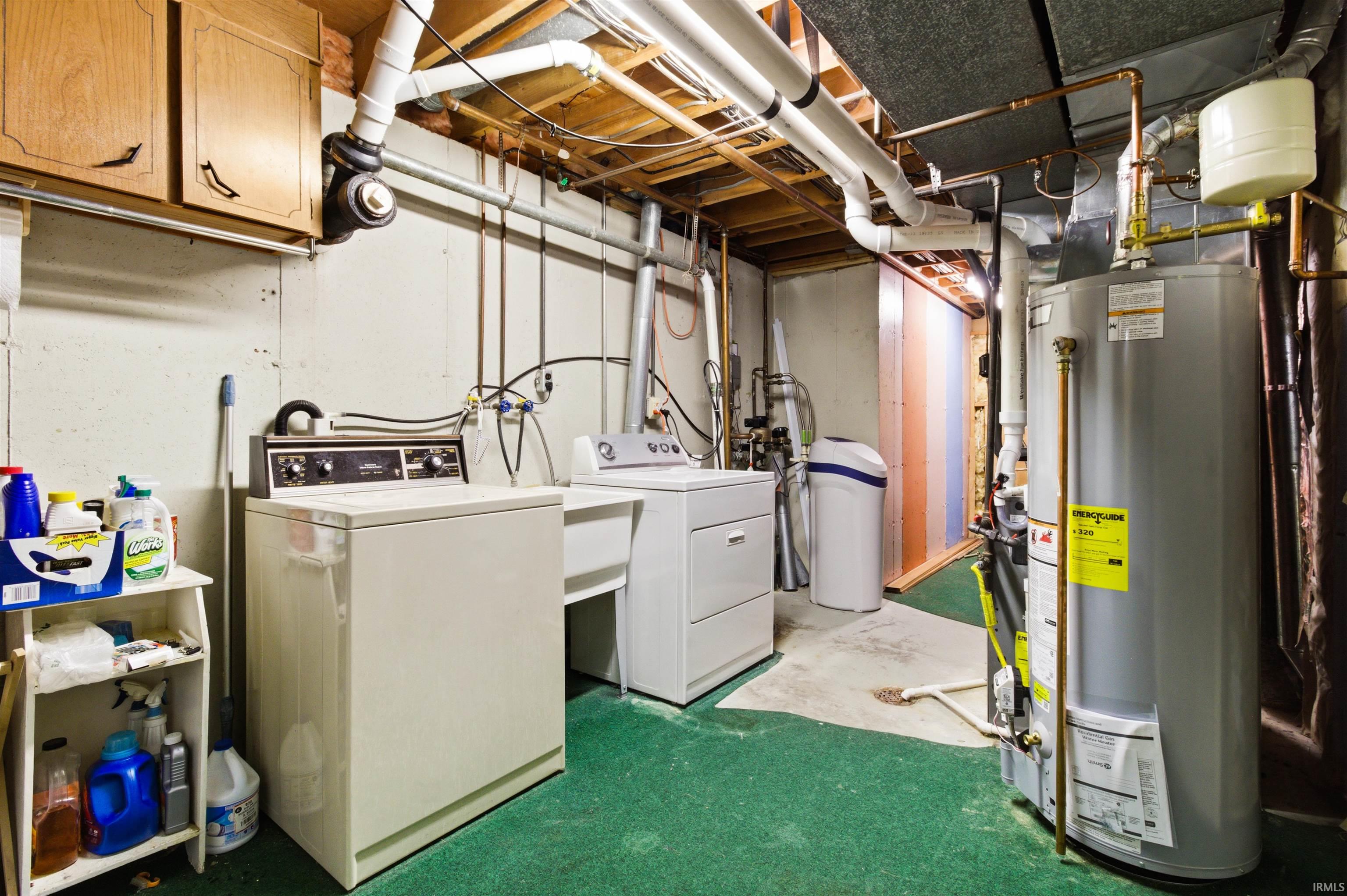 Dedicated utility room featuring a washing machine, dryer, utility sink, water heater, and water softener