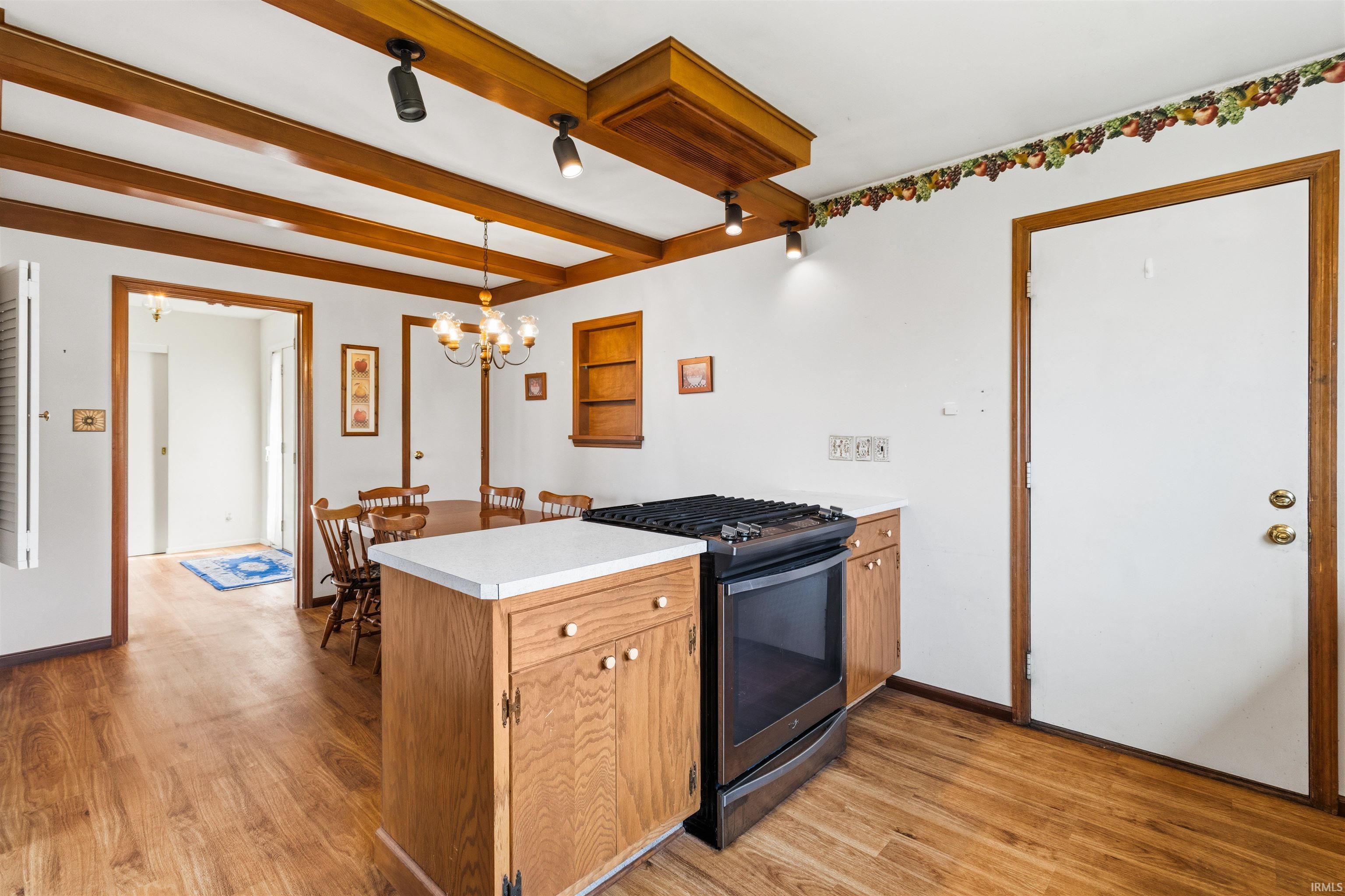 Kitchen featuring a stainless steel range, white countertops, wood-finish flooring, exposed ceiling beams, and recessed lighting