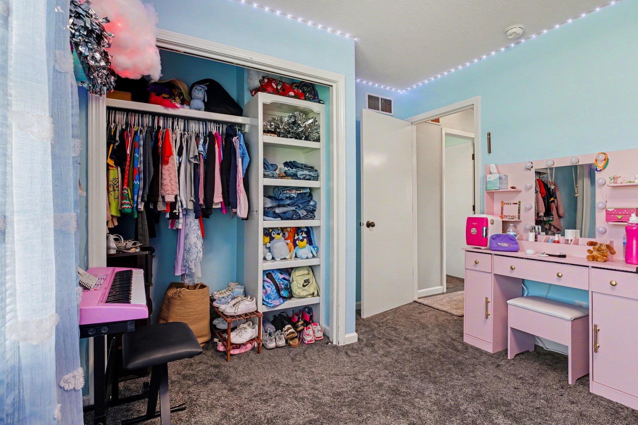 Recessed closet with integrated shelving, gray carpeting, and light blue wall paint