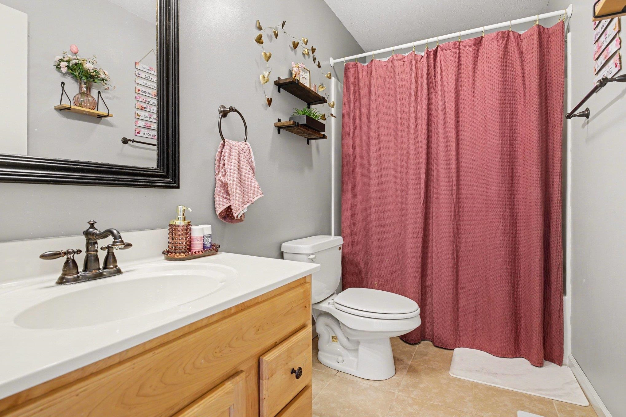 Bathroom with a wood-finish vanity, white countertop, and integrated sink