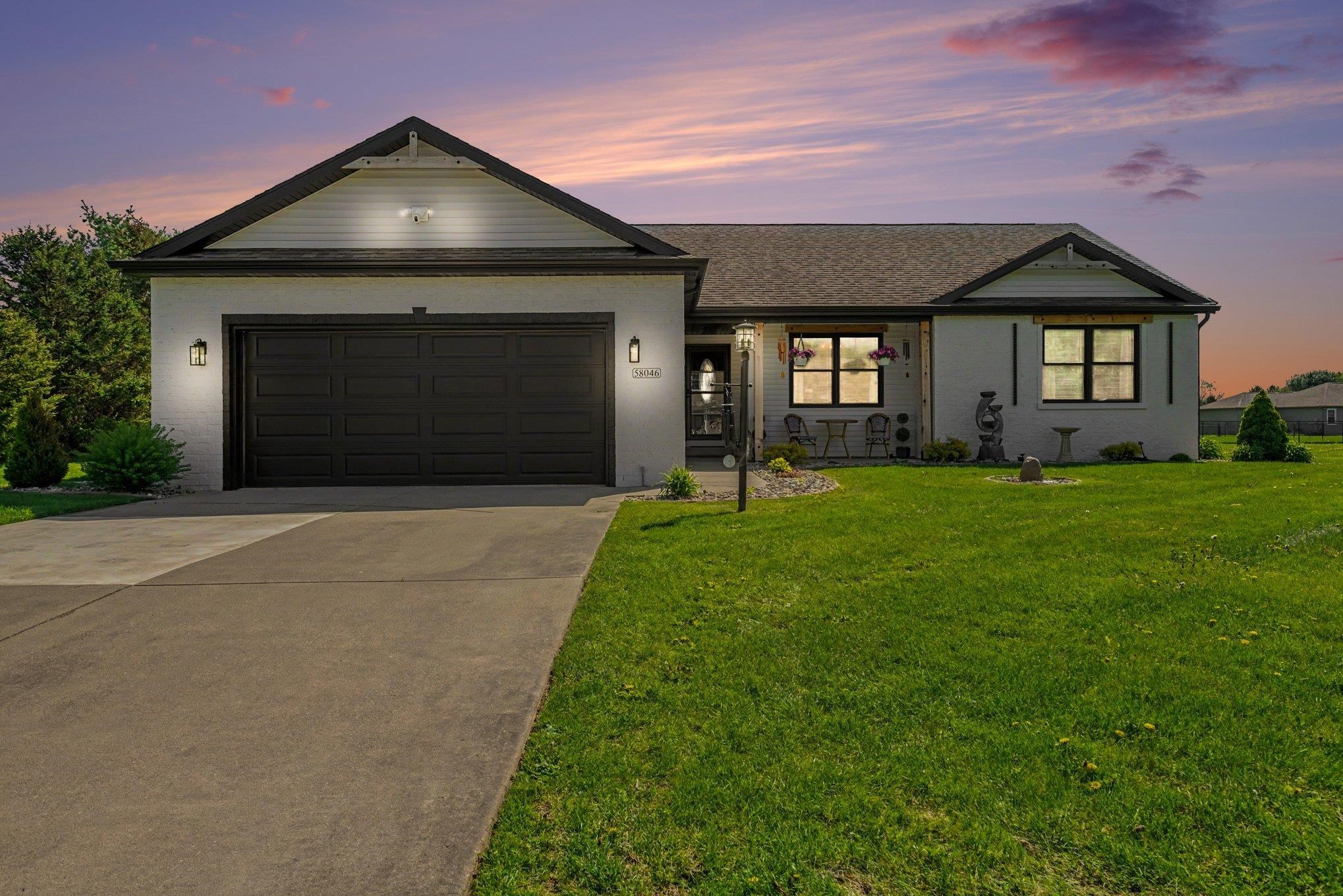 Contemporary ranch-style residence featuring a two-car garage, concrete driveway, and a manicured lawn
