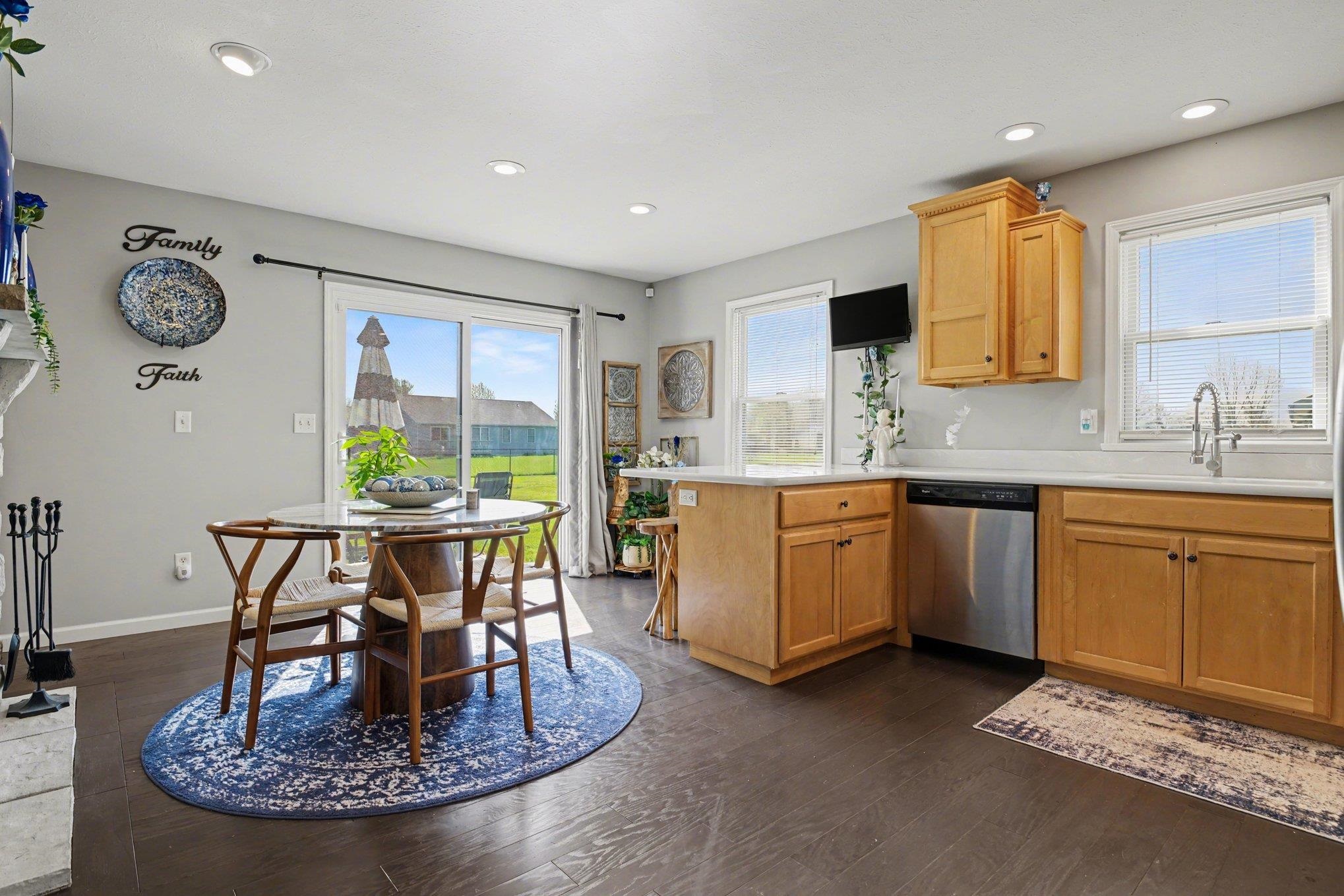 Open-concept kitchen and dining area featuring dark wood-finish flooring, light wood cabinetry, and light-colored countertops