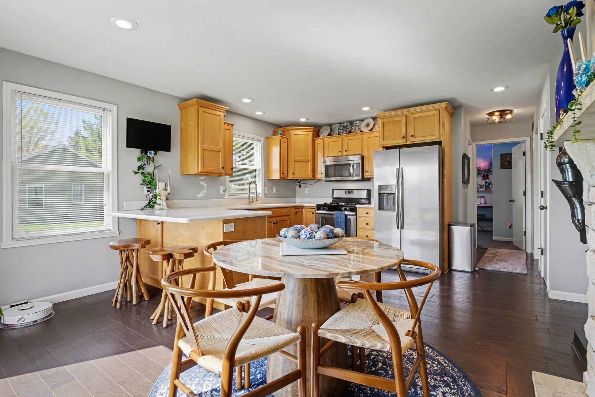Open-concept kitchen featuring wood-finish cabinetry, stainless steel appliances, light-toned countertops, recessed lighting, and dark wood-finish flooring