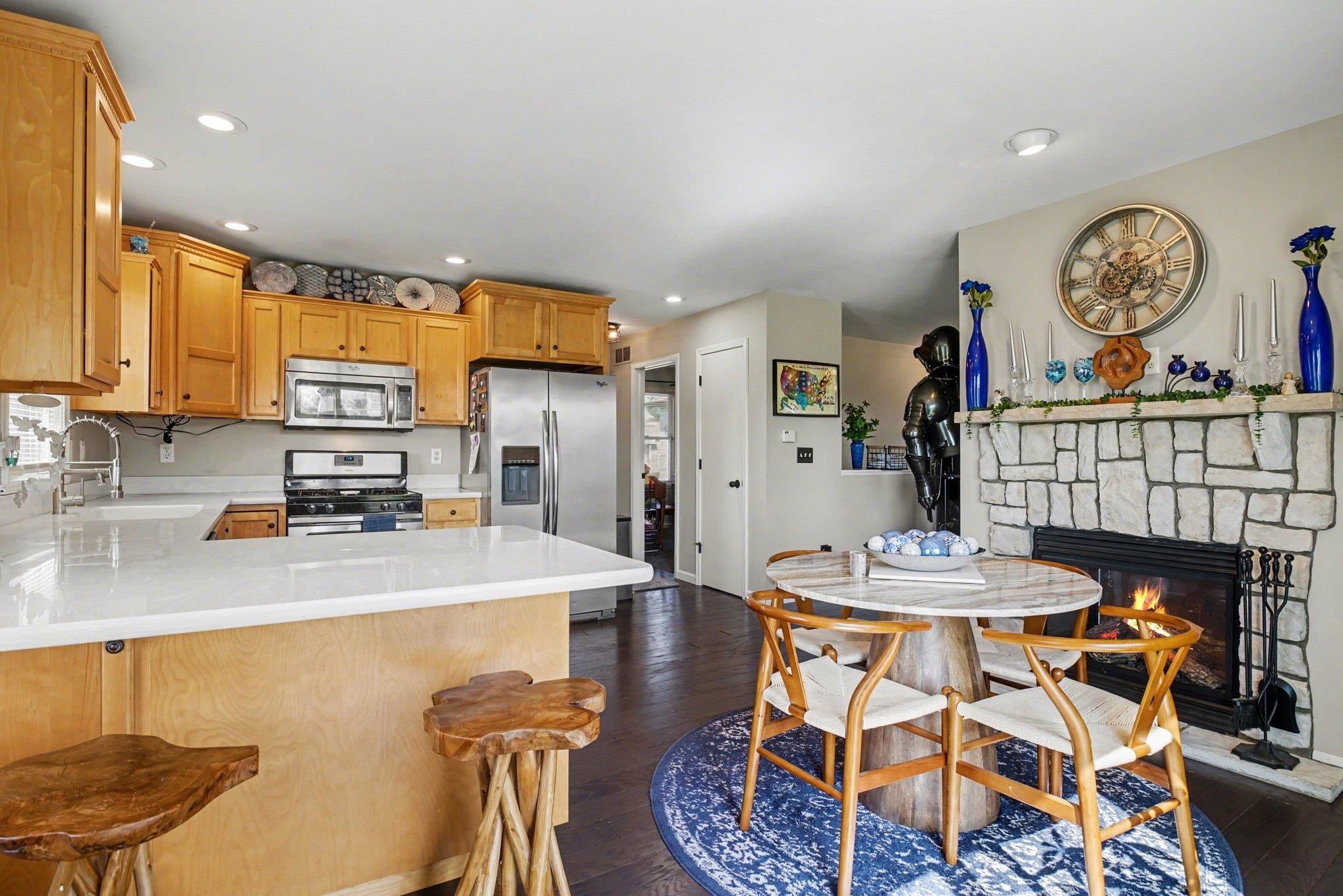 Open-concept kitchen and dining area featuring a stone fireplace