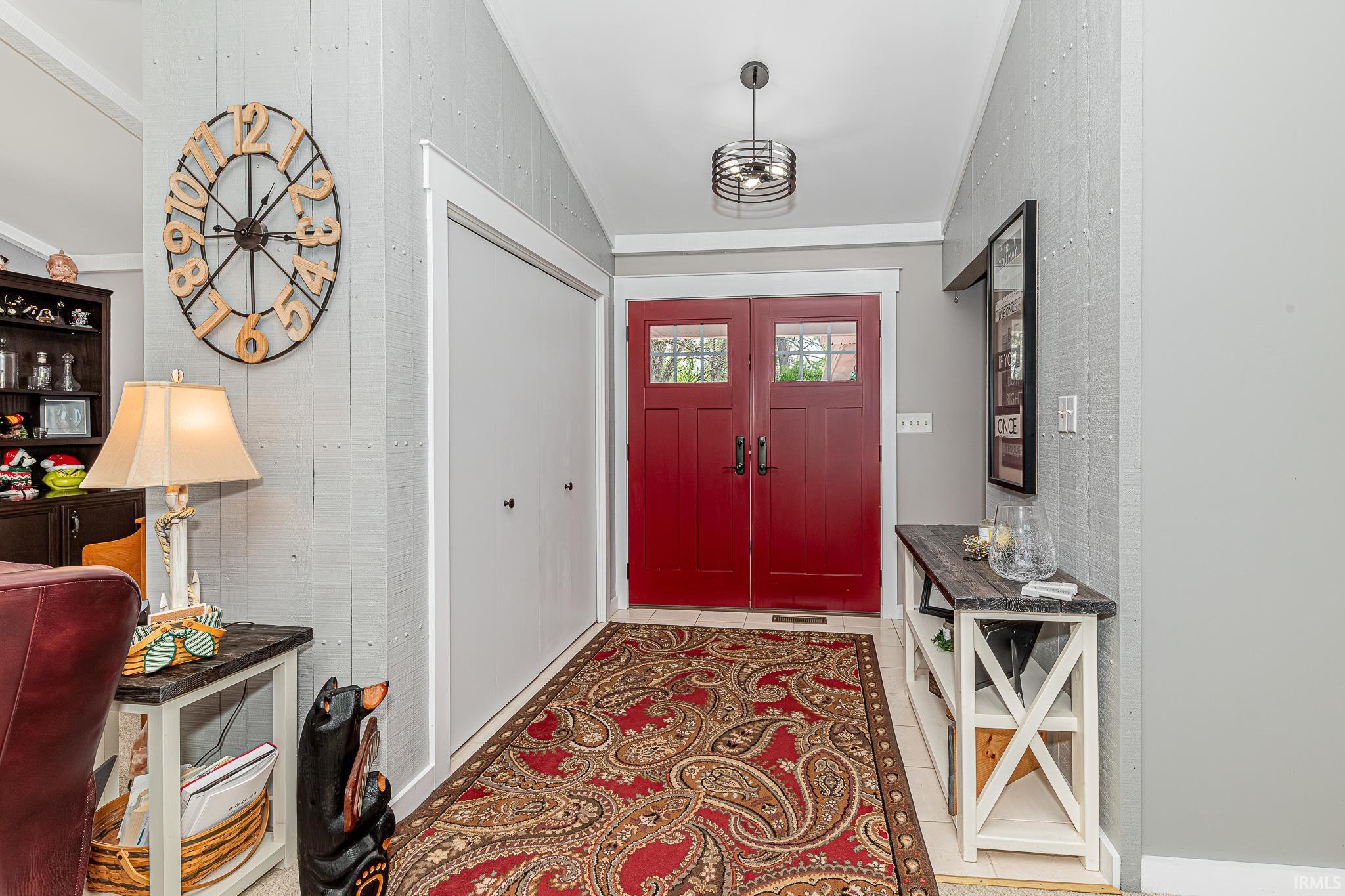 Entryway featuring double red doors with glass inserts, a contemporary drum pendant light fixture, and a built-in closet with white bifold doors