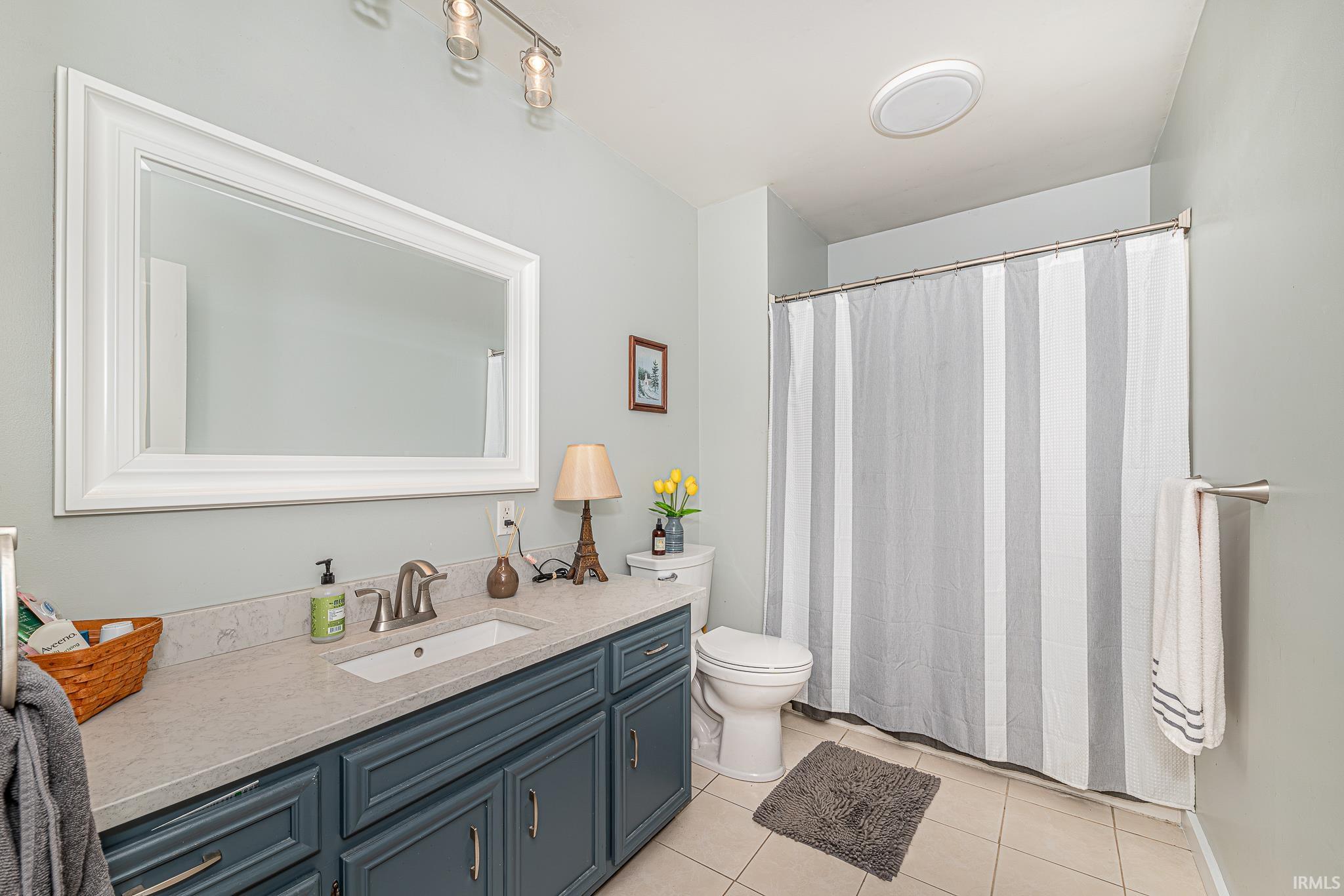 Bathroom featuring a vanity with a light-toned countertop, integrated sink, and dark-paneled cabinetry