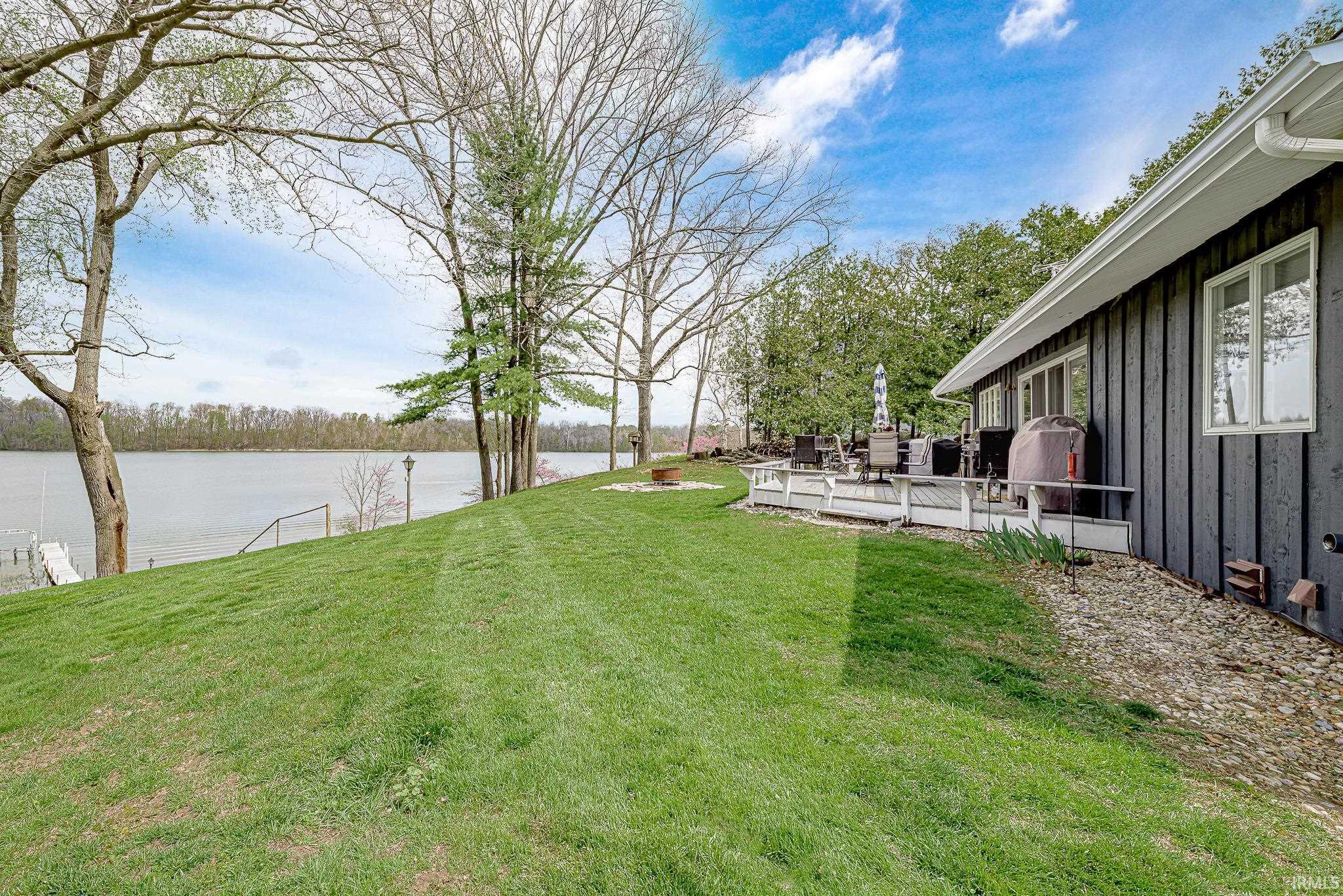 Expansive waterfront property featuring a sloped lawn leading to a private dock