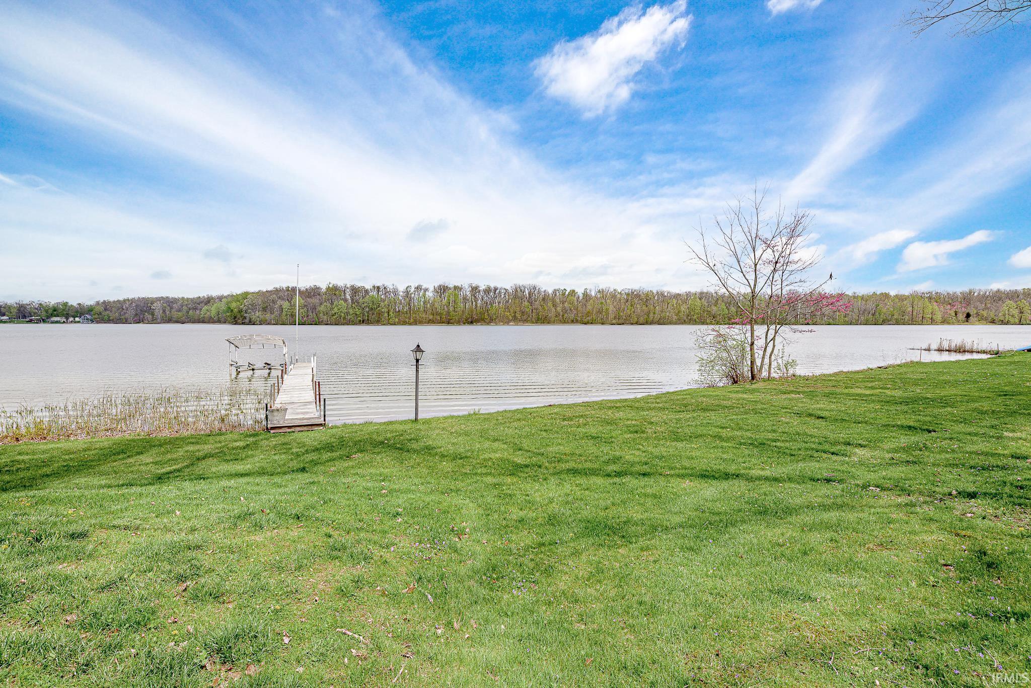Expansive waterfront property featuring a private dock and a grassy lawn