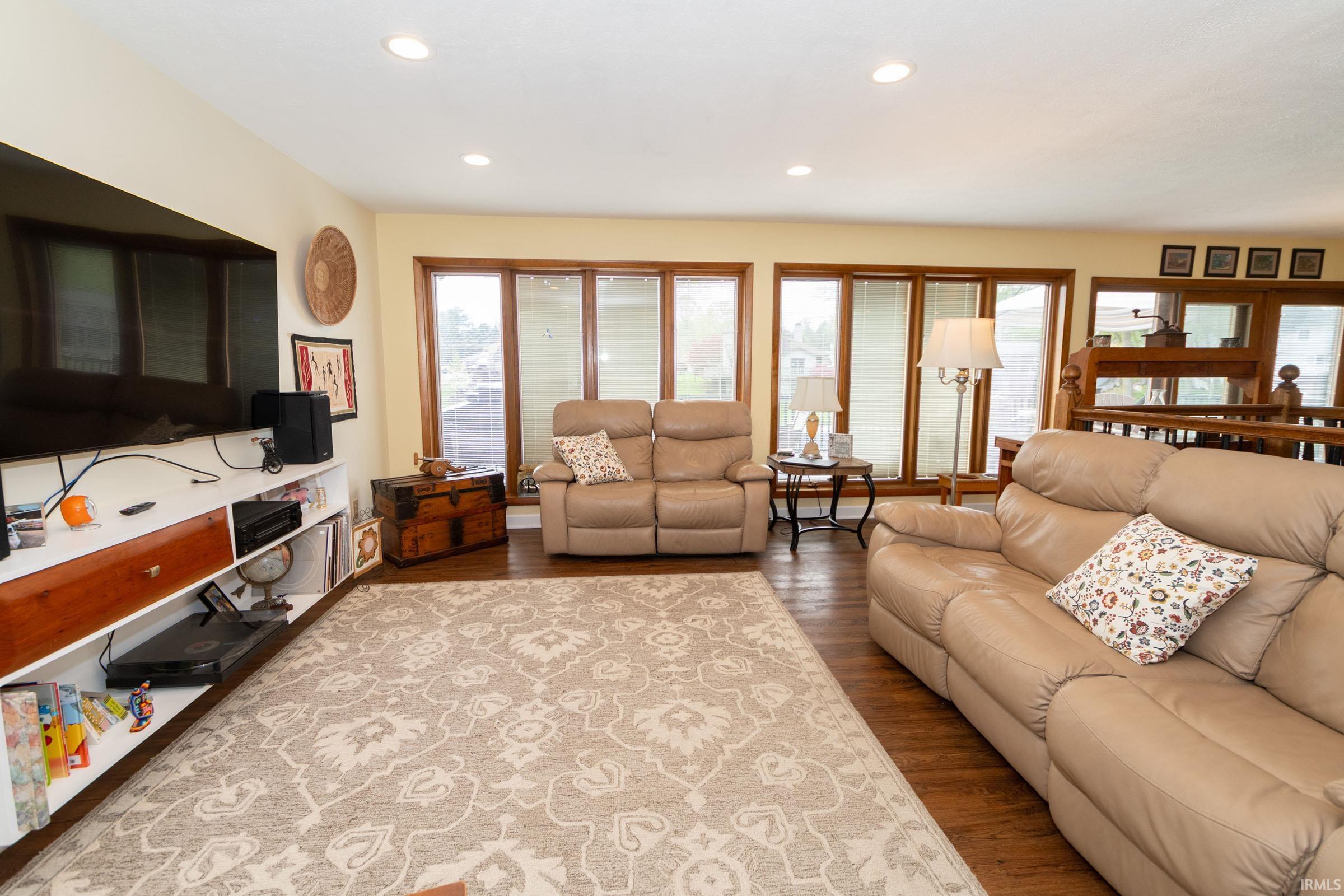 Spacious living area featuring warm wood-finish flooring and ample natural light from multiple windows