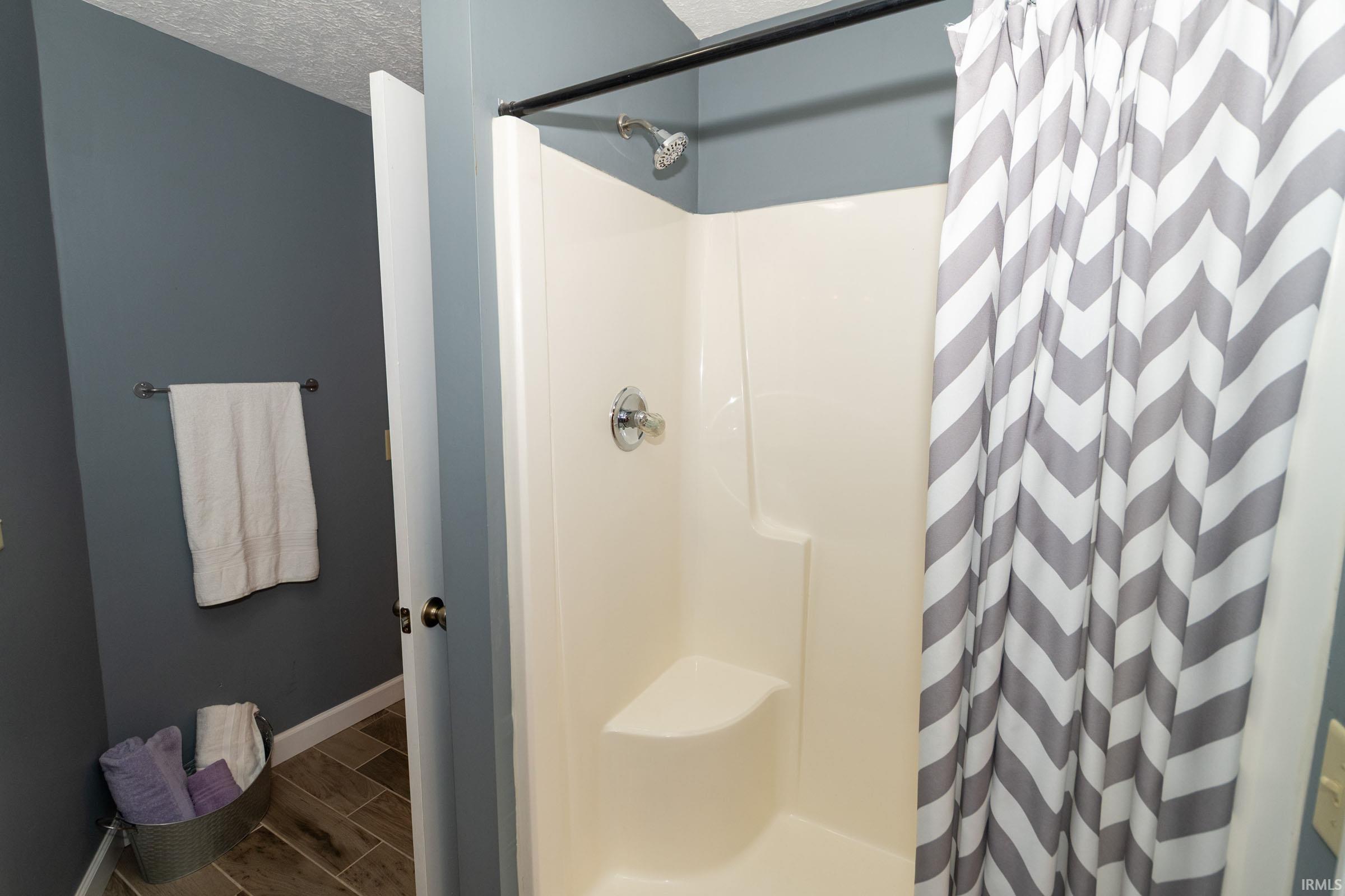 Bathroom with a white shower stall featuring a built-in seat and chrome fixtures