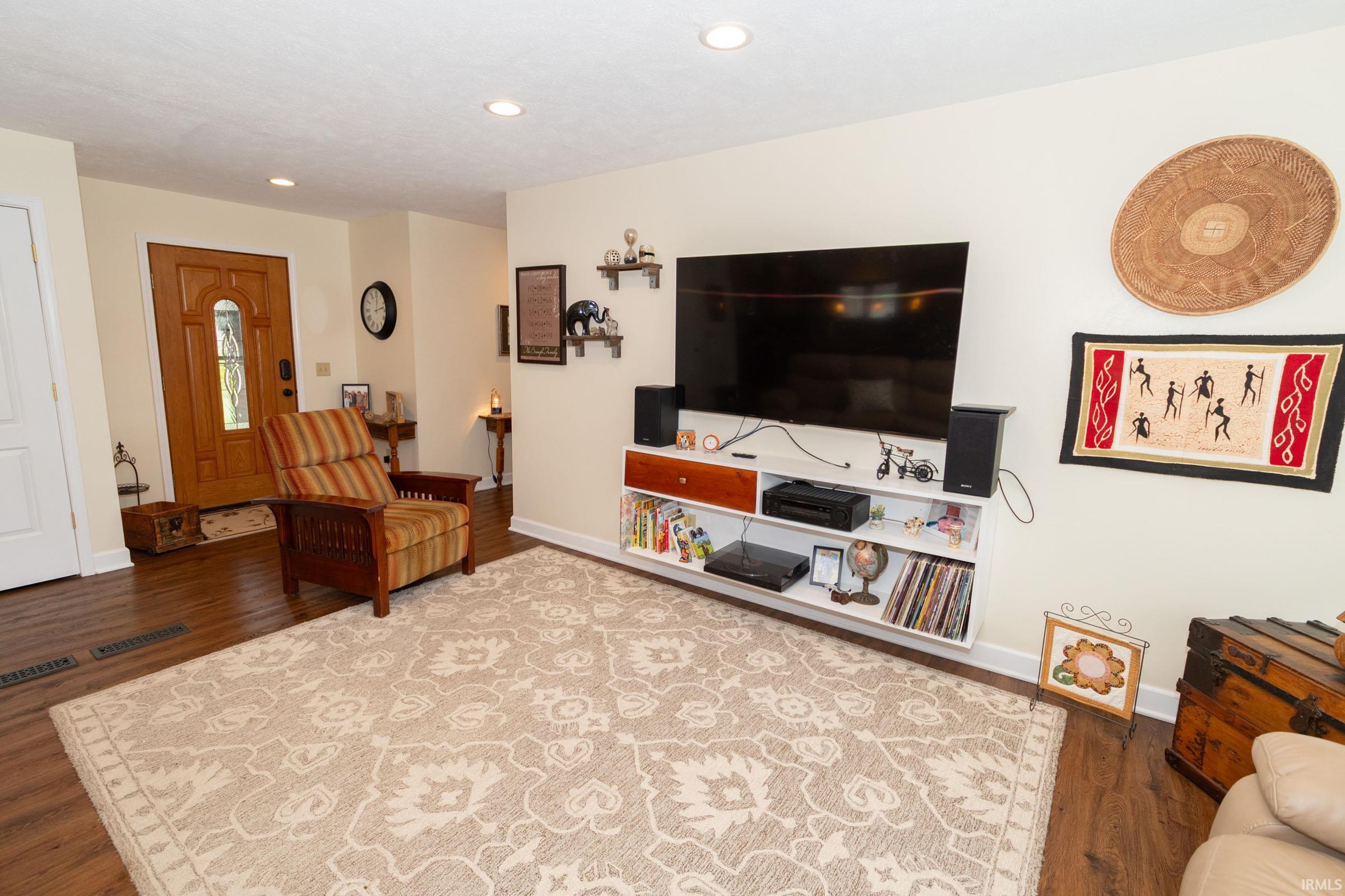 Living area featuring wood-finish flooring, recessed lighting, and a built-in media console with white shelving and wood-tone drawers