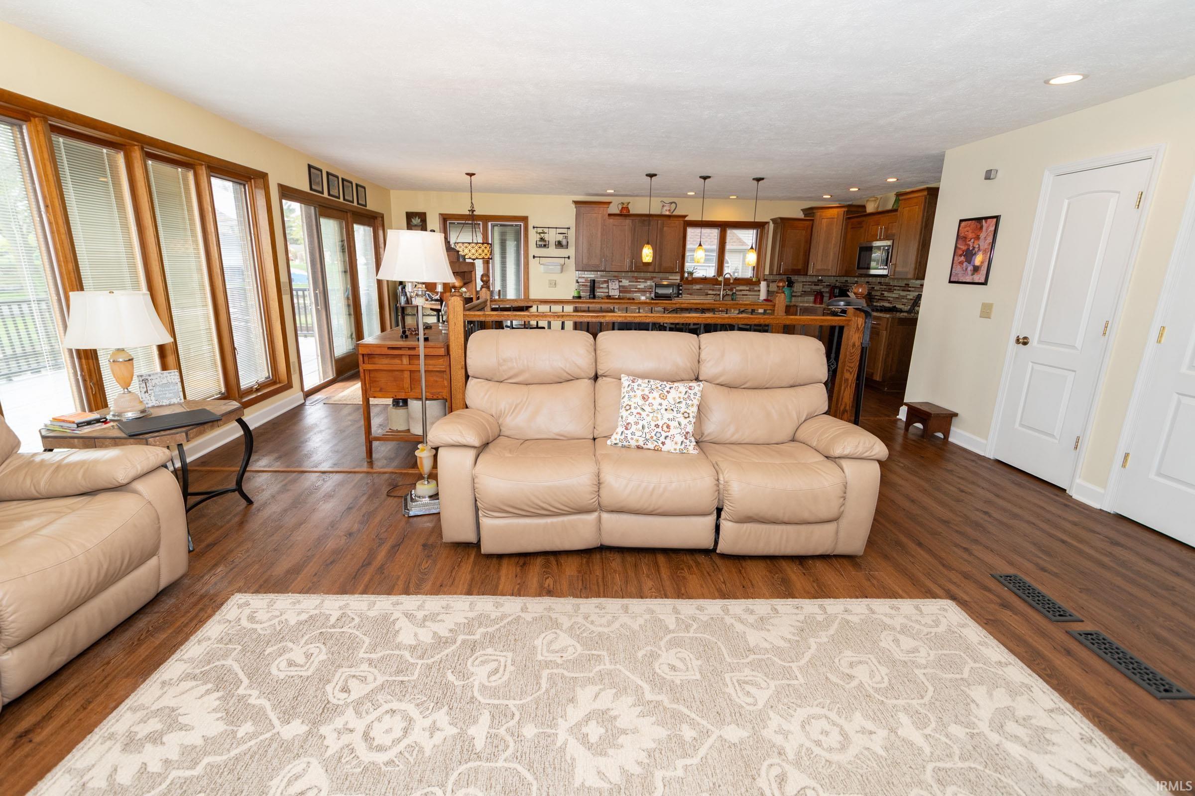 Open-concept living area with wood-finish flooring, recessed lighting, and a neutral color palette