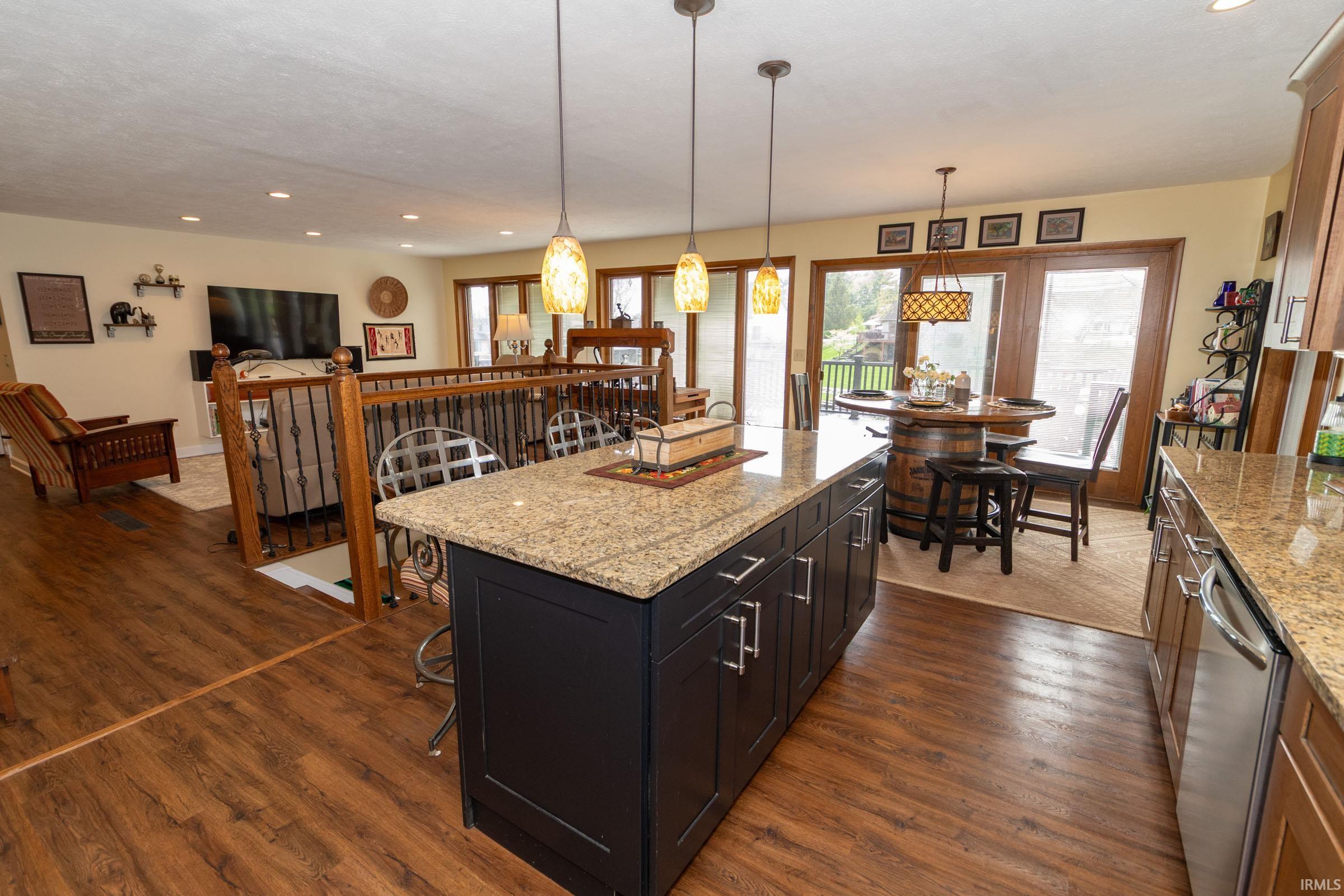 Kitchen island with a light-toned countertop, dark base cabinetry, and pendant lighting