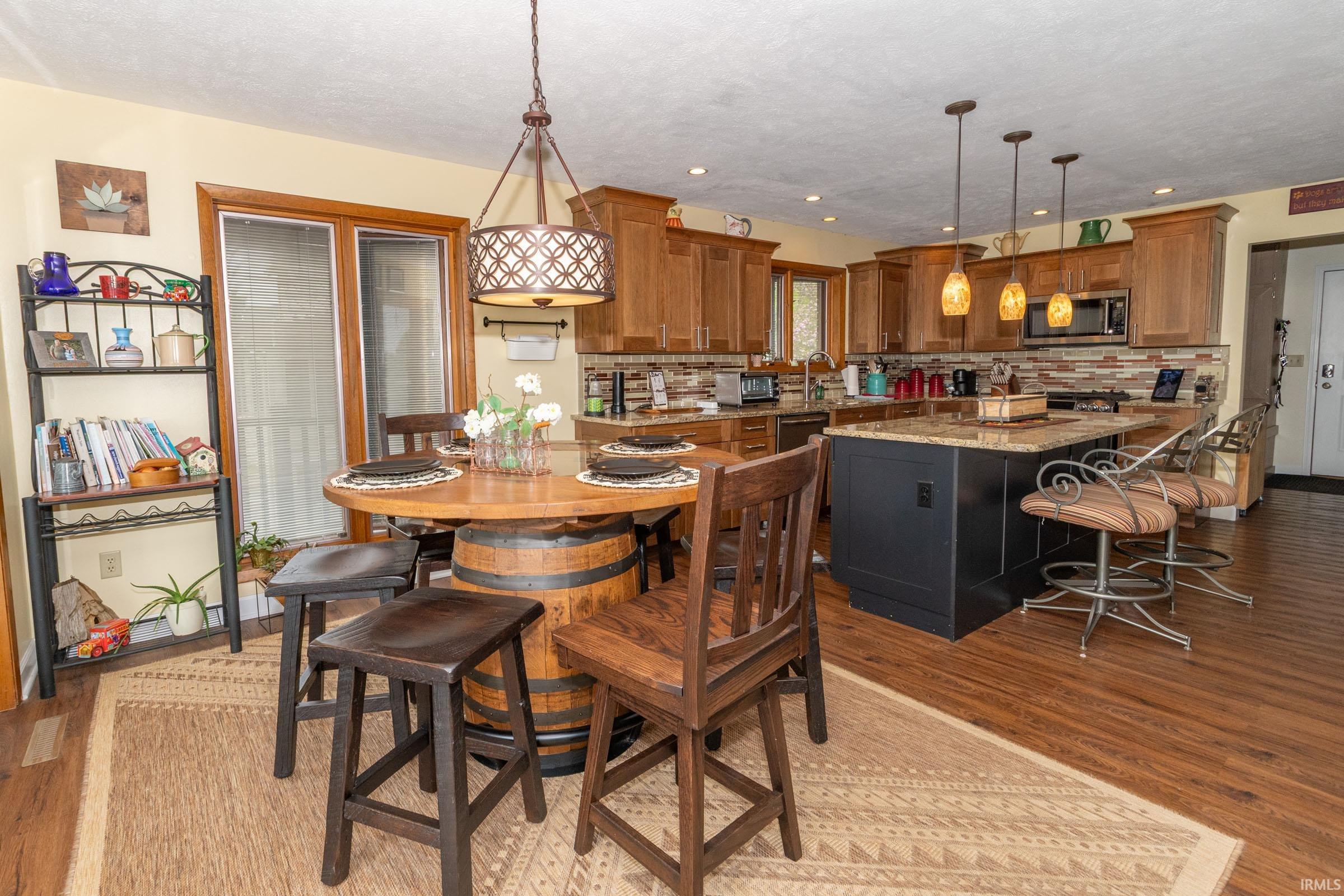 Kitchen featuring wood-finish flooring, recessed lighting, and a dark-toned island with a light-toned countertop