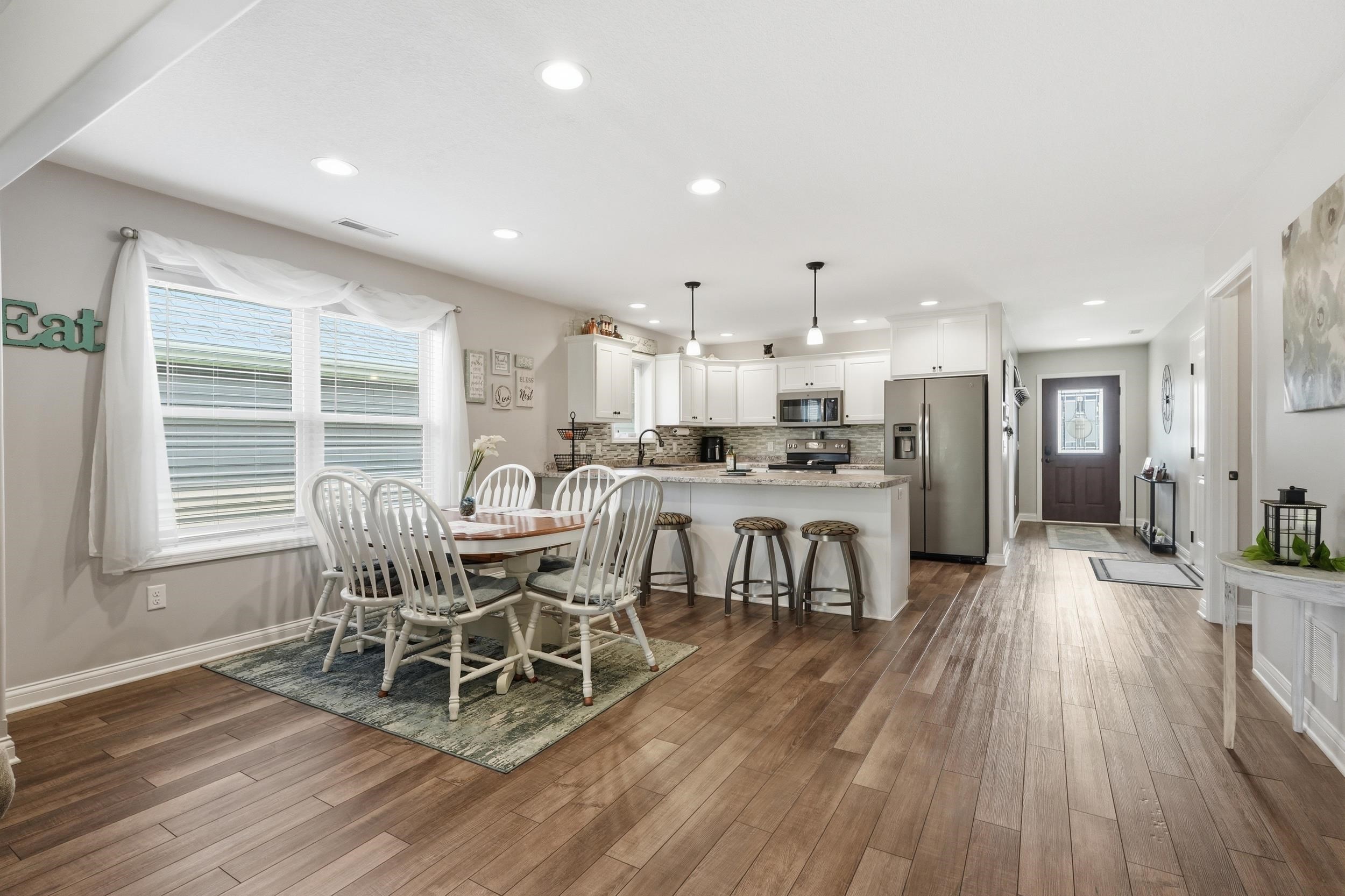 Open-concept living area featuring wood-finish flooring, recessed lighting, and a kitchen island with pendant lights