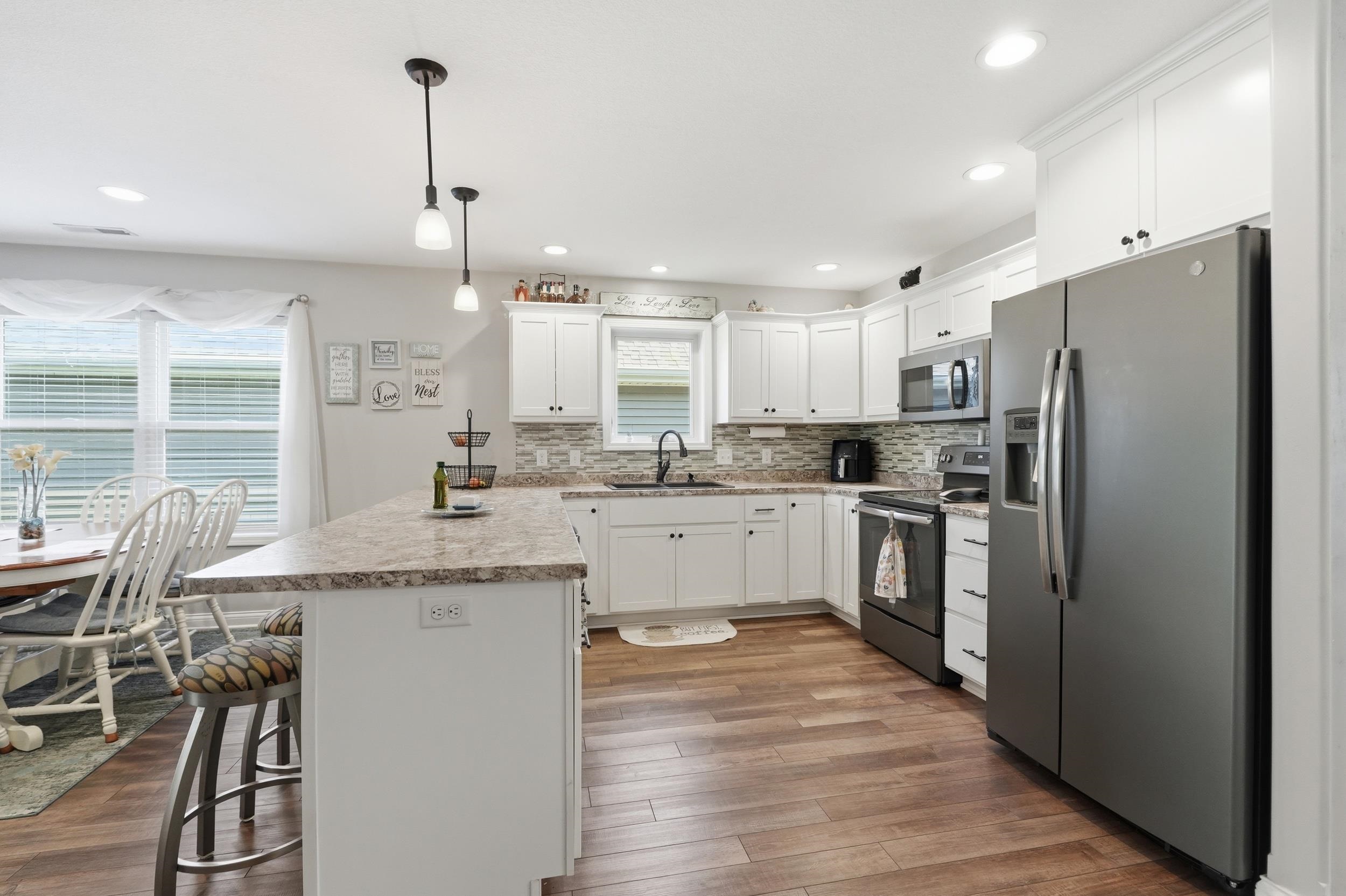 Kitchen featuring white cabinetry, stone-look countertops, a tile backsplash, and wood-finish flooring