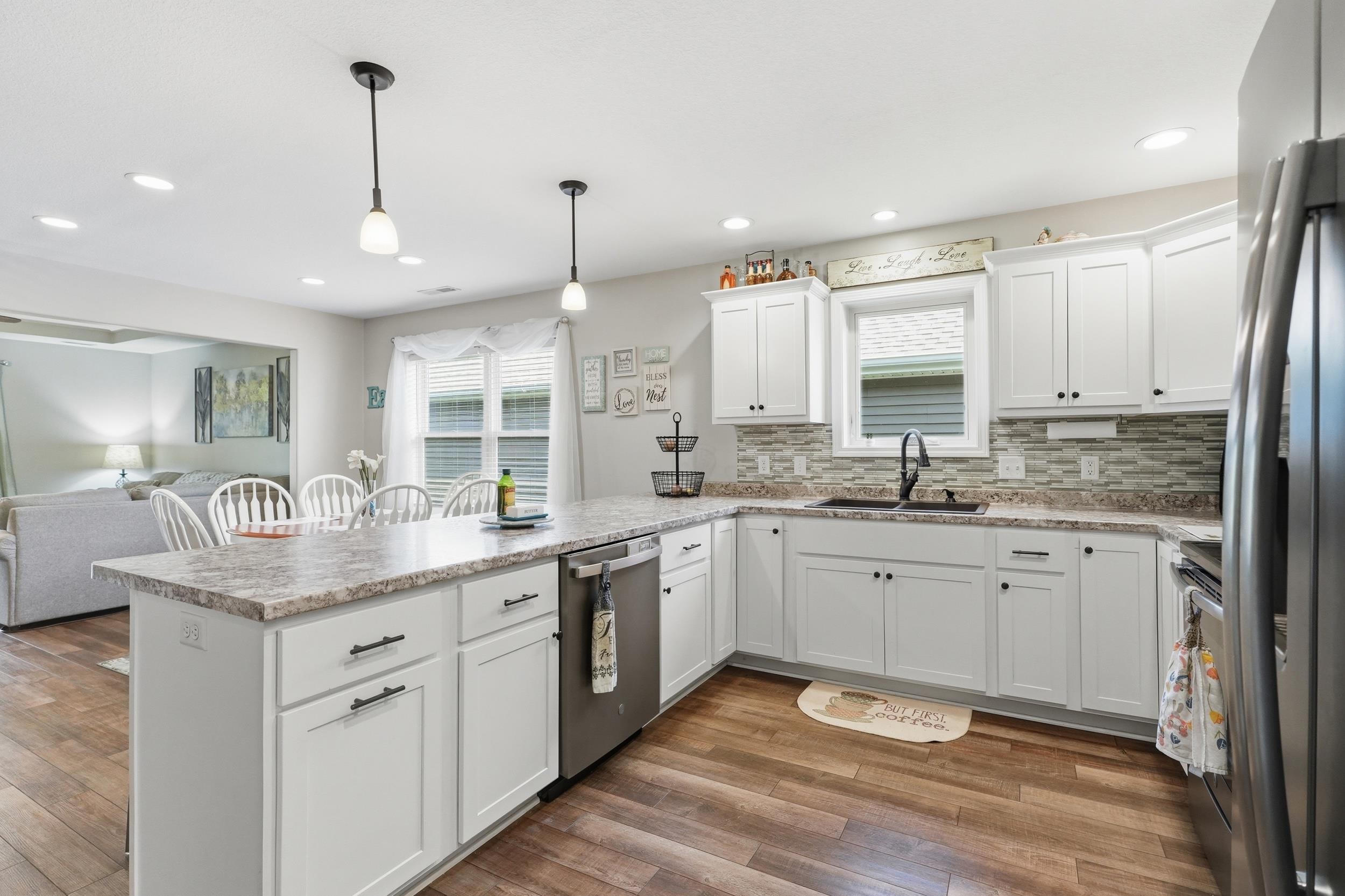 Kitchen featuring an island with seating, white cabinetry, a tile backsplash, wood-finish flooring, and recessed lighting