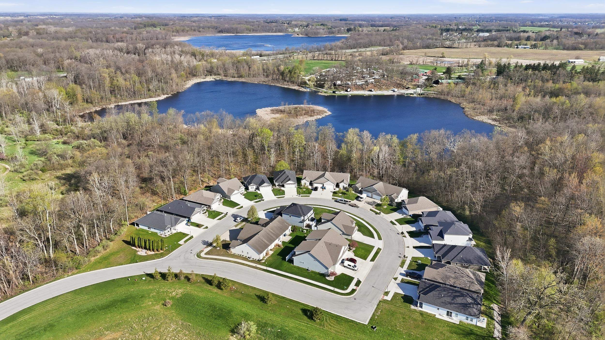 Aerial perspective showcasing a circular residential development surrounded by mature trees and two distinct bodies of water