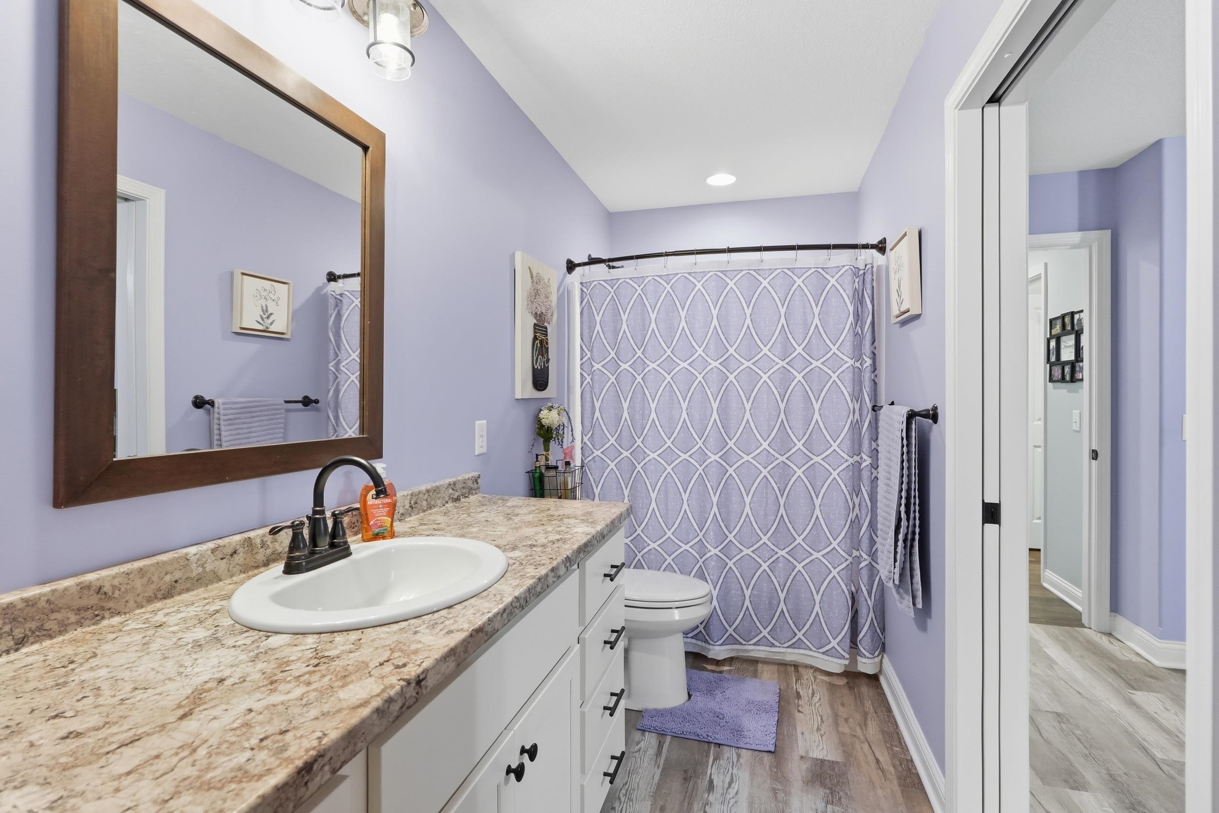 Bathroom featuring a vanity with an integrated sink, a large framed mirror, and a shower-tub combination