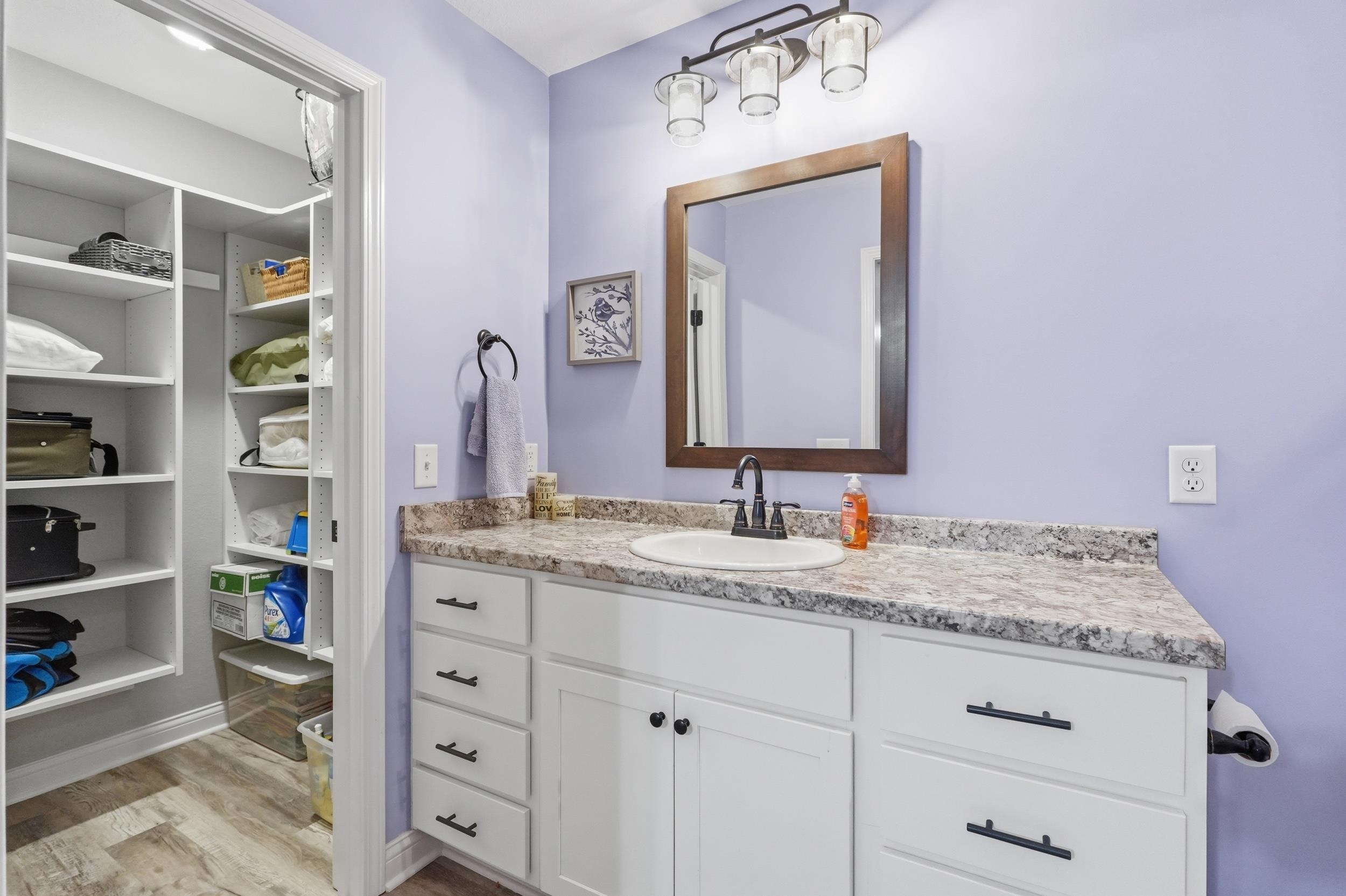 Bathroom vanity featuring a single basin sink, speckled countertop, and white cabinetry with matte black hardware