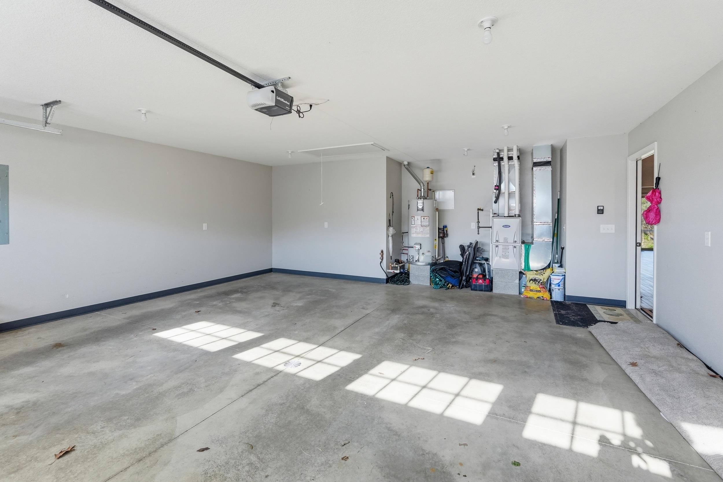 Spacious garage featuring a concrete floor, light gray walls, and a visible garage door opener system