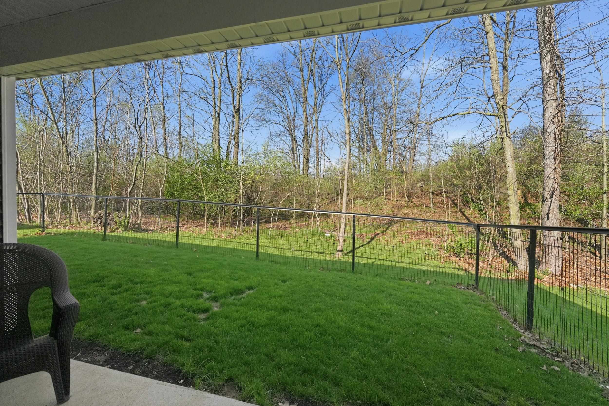 Covered patio featuring concrete flooring and a black metal perimeter fence