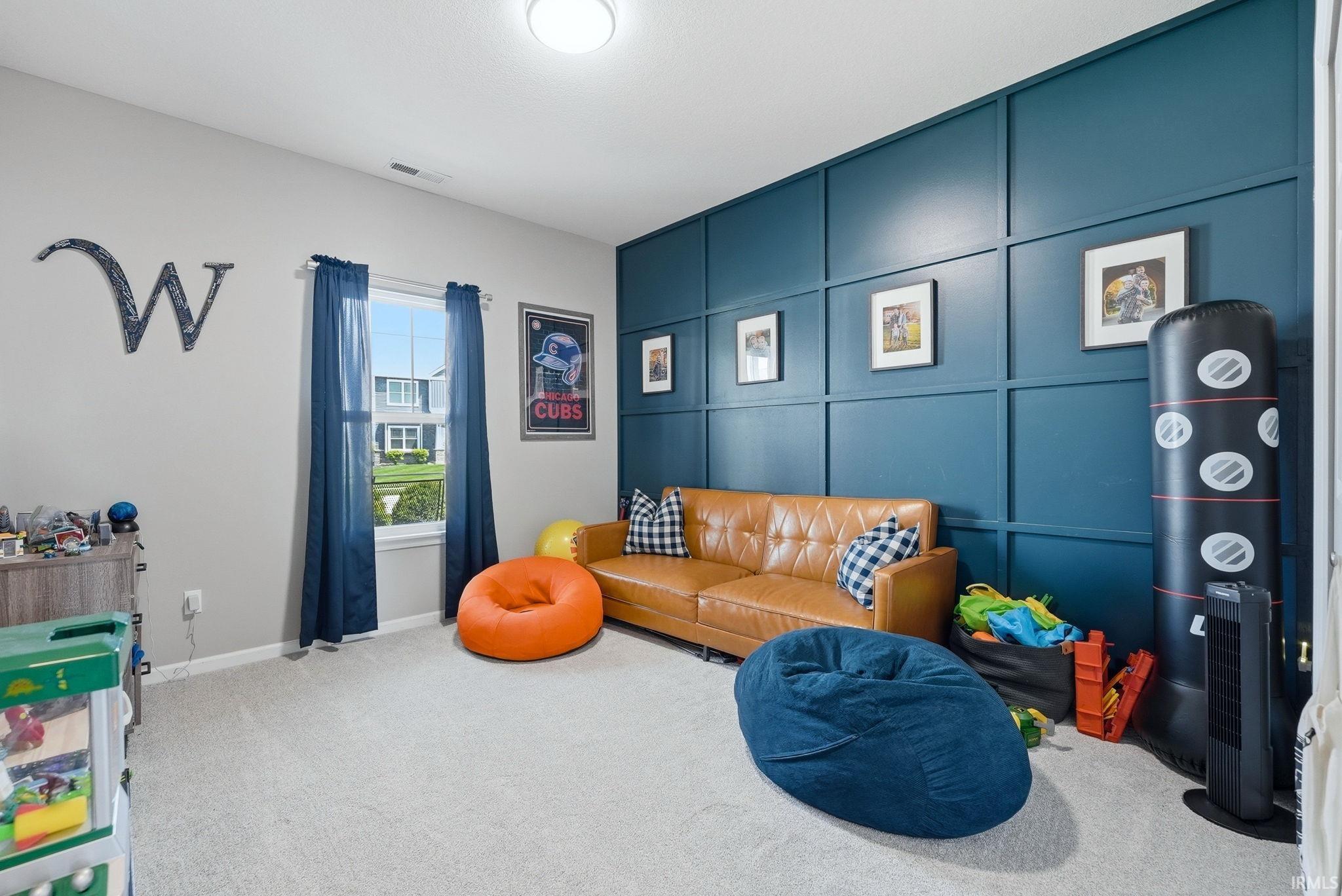 Room featuring a prominent accent wall with panel molding, light gray wall finishes, and light-colored carpeting