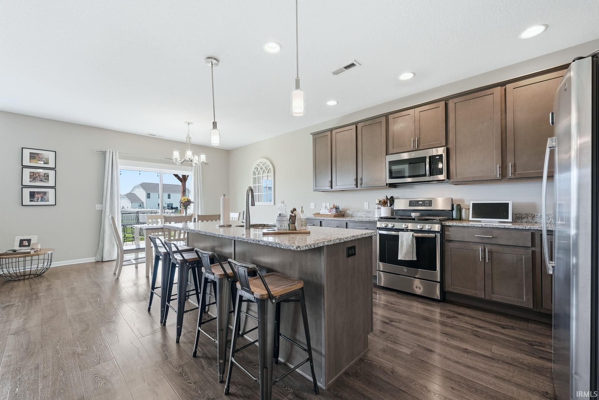Kitchen featuring a central island with countertop seating, wood-finish flooring, and recessed lighting