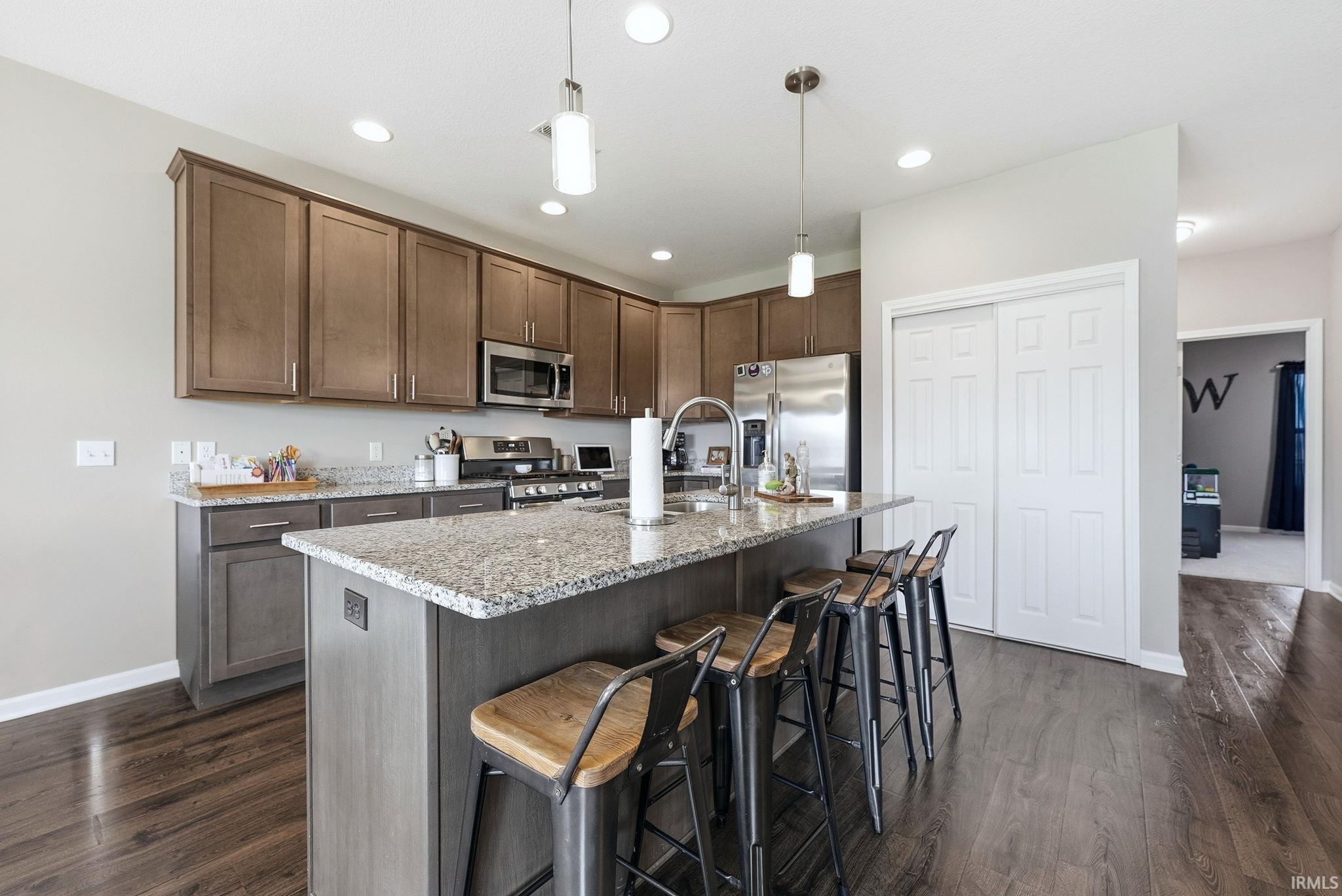 Contemporary kitchen featuring wood-finish flooring, granite countertops, stainless steel appliances, and abundant cabinetry