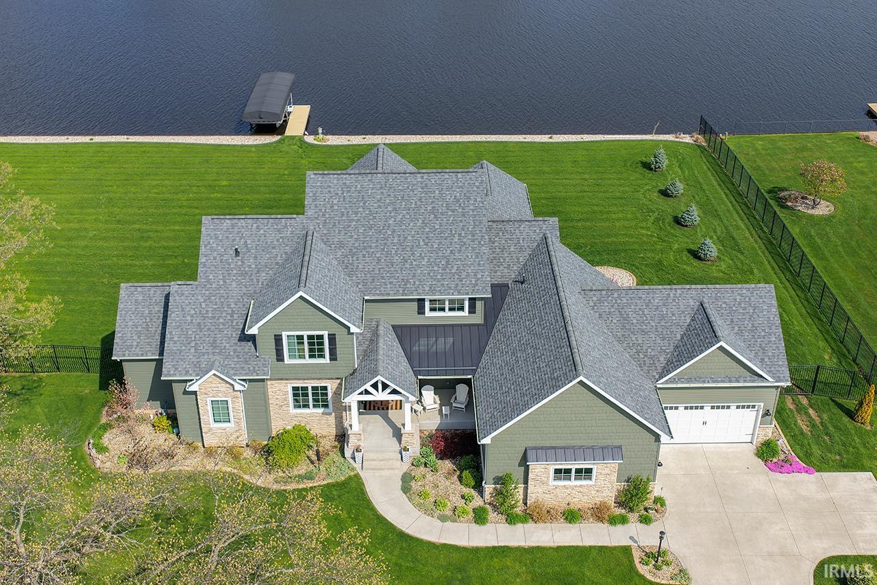 Expansive waterfront property featuring a large residence with varied rooflines and a three-car garage