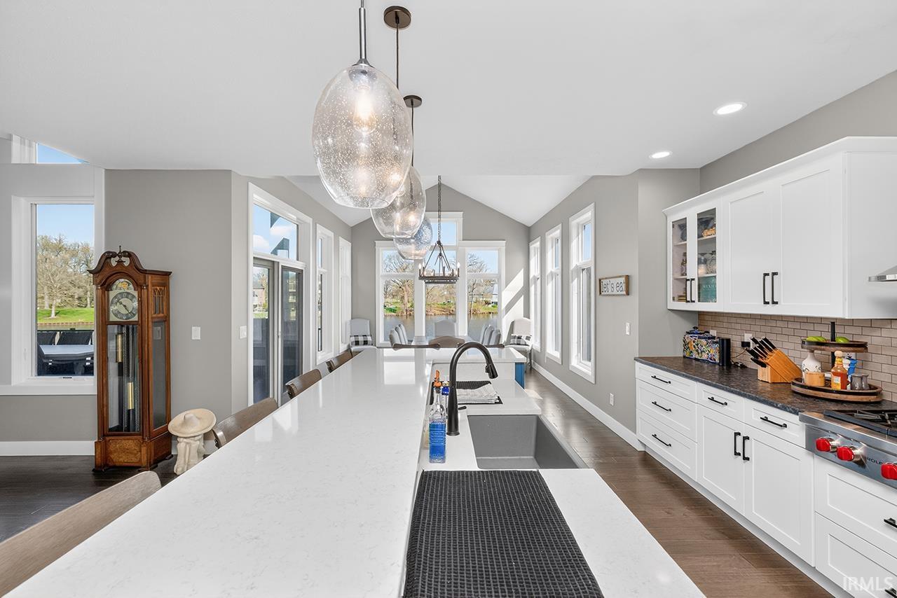 Gourmet kitchen featuring an oversized island with an integrated sink, pendant lighting, and crisp white cabinetry
