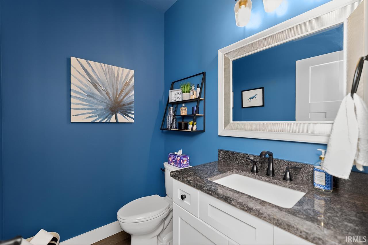 Half Bathroom featuring a white vanity with a dark speckled countertop, undermount sink, and matte black faucet