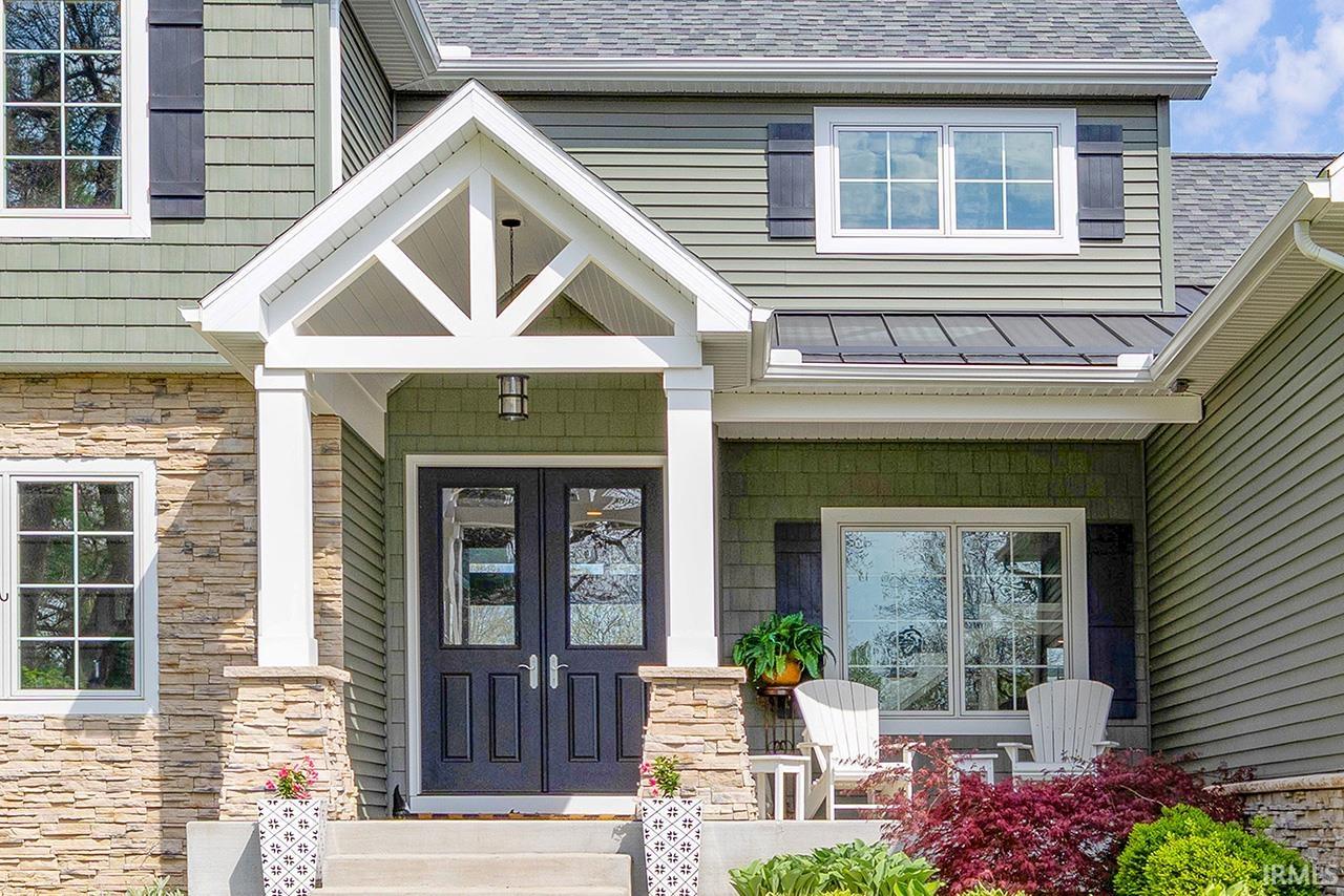 Craftsman-style entry with stone veneer accents, double pane windows, and a covered porch featuring decorative gable trusses