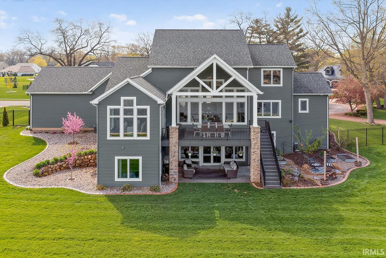Expansive rear exterior featuring a two-story design with multiple windows, a covered upper-level deck, and a lower-level patio