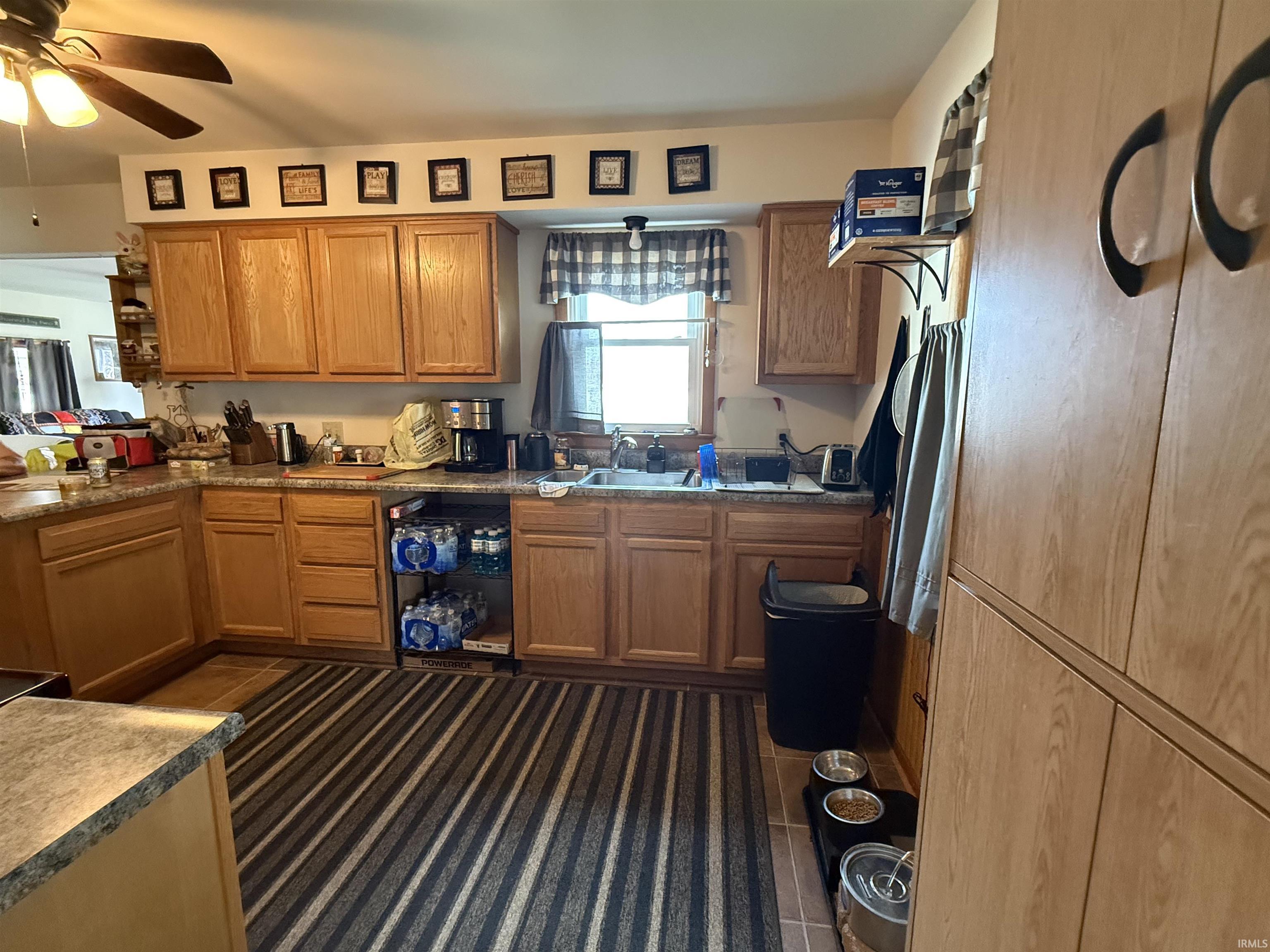 Kitchen featuring wood cabinetry, laminate countertops, a double-basin sink, and a ceiling fan with integrated lighting