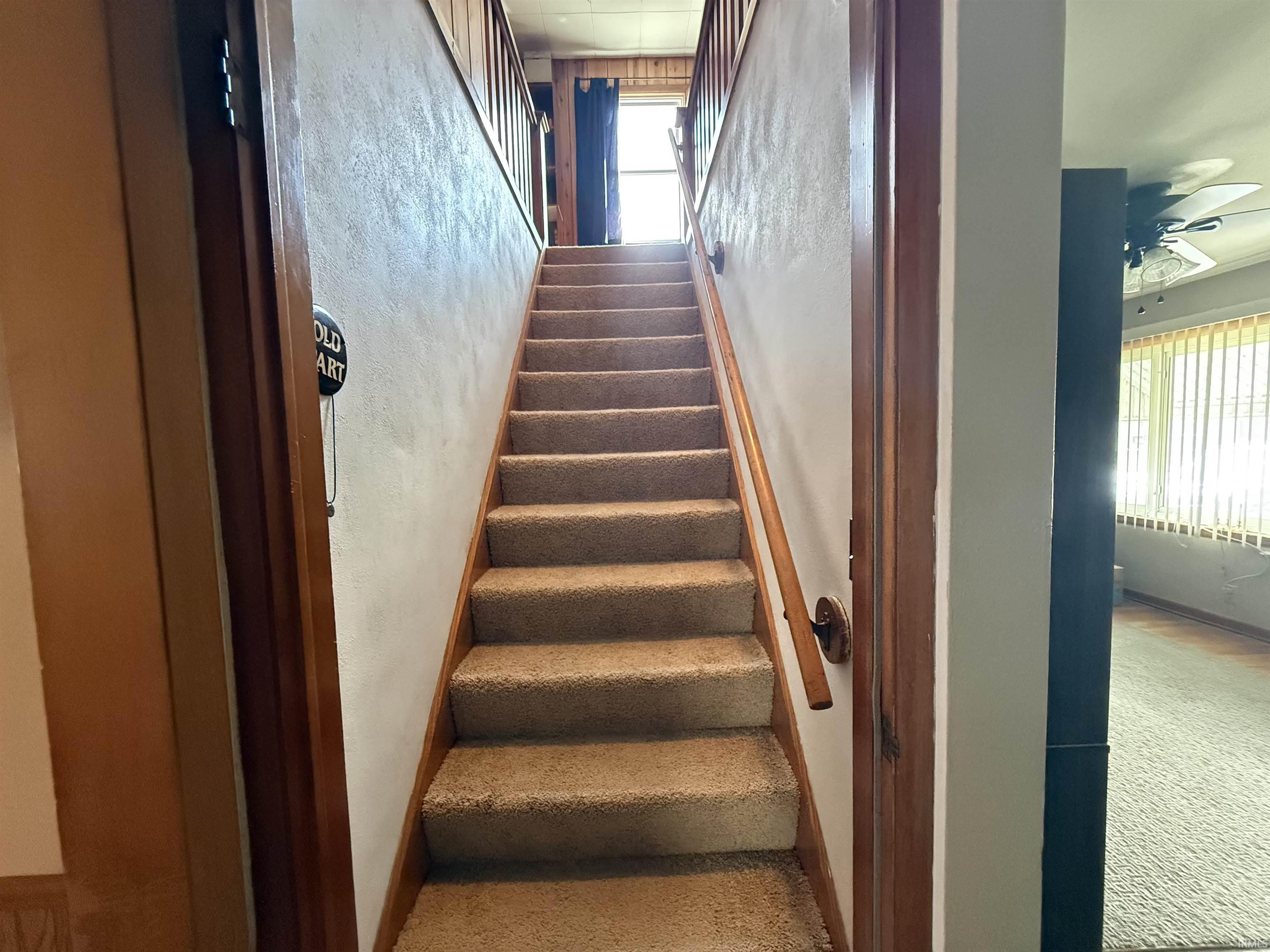 Carpeted stairway with wood handrail and wood trim