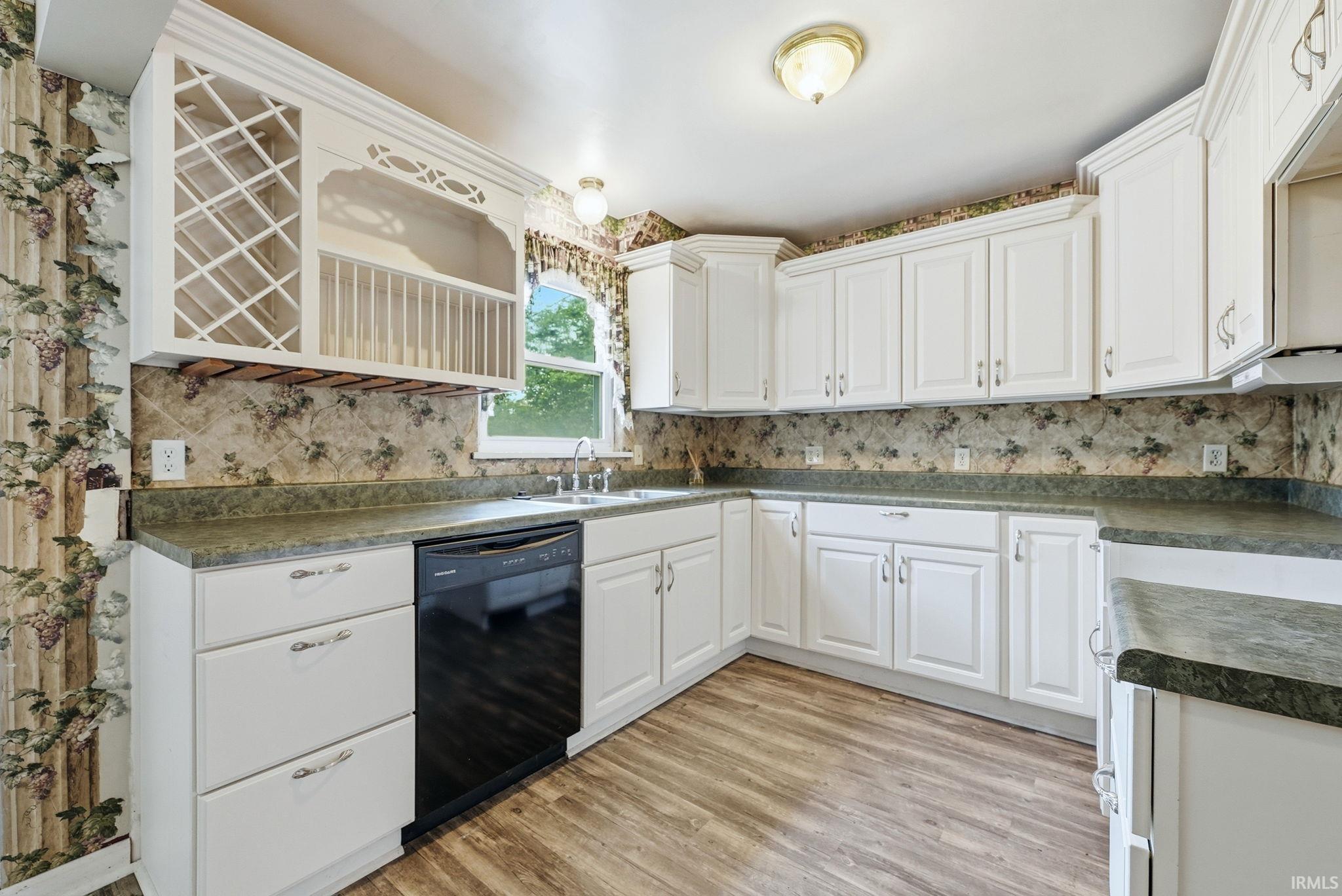 Kitchen featuring abundant white cabinetry, dark countertops, a built-in wine rack, wood-finish flooring, and a black dishwasher