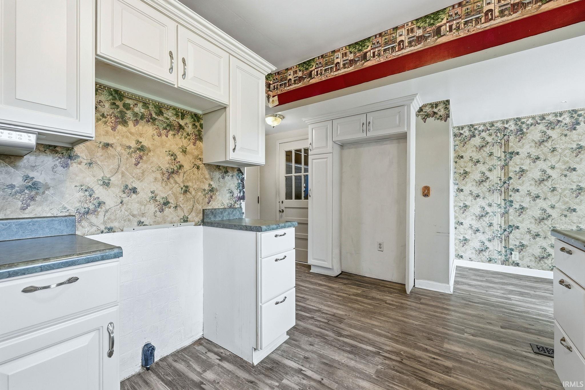 Kitchen area featuring white cabinetry, grey wood-finish flooring, and a built-in refrigerator cabinet