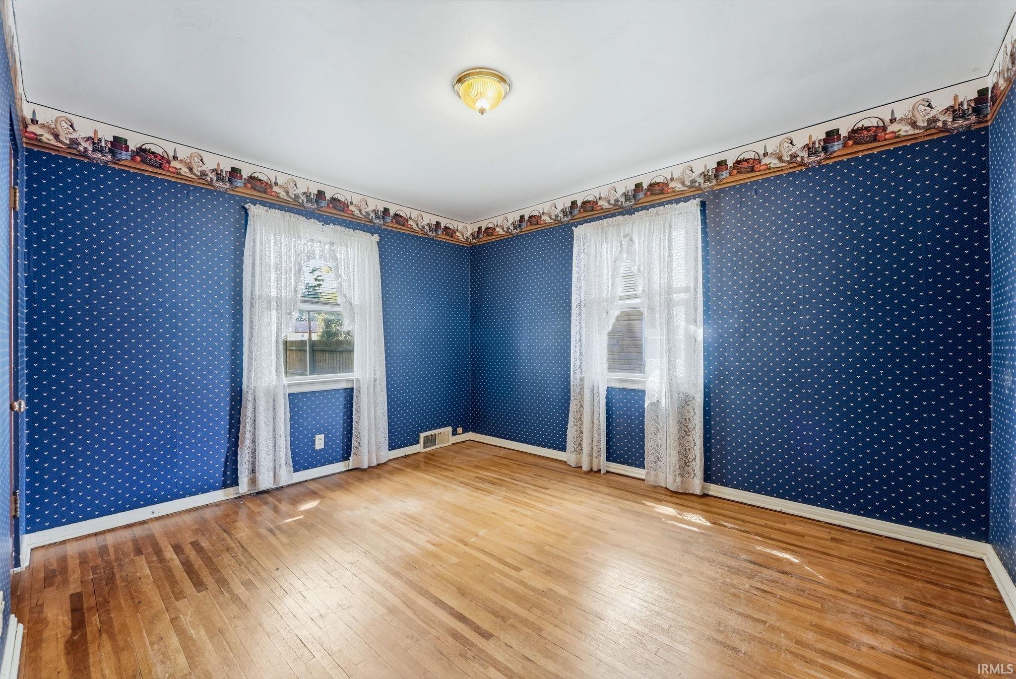 Spacious room featuring wood-finish flooring and two windows providing natural light