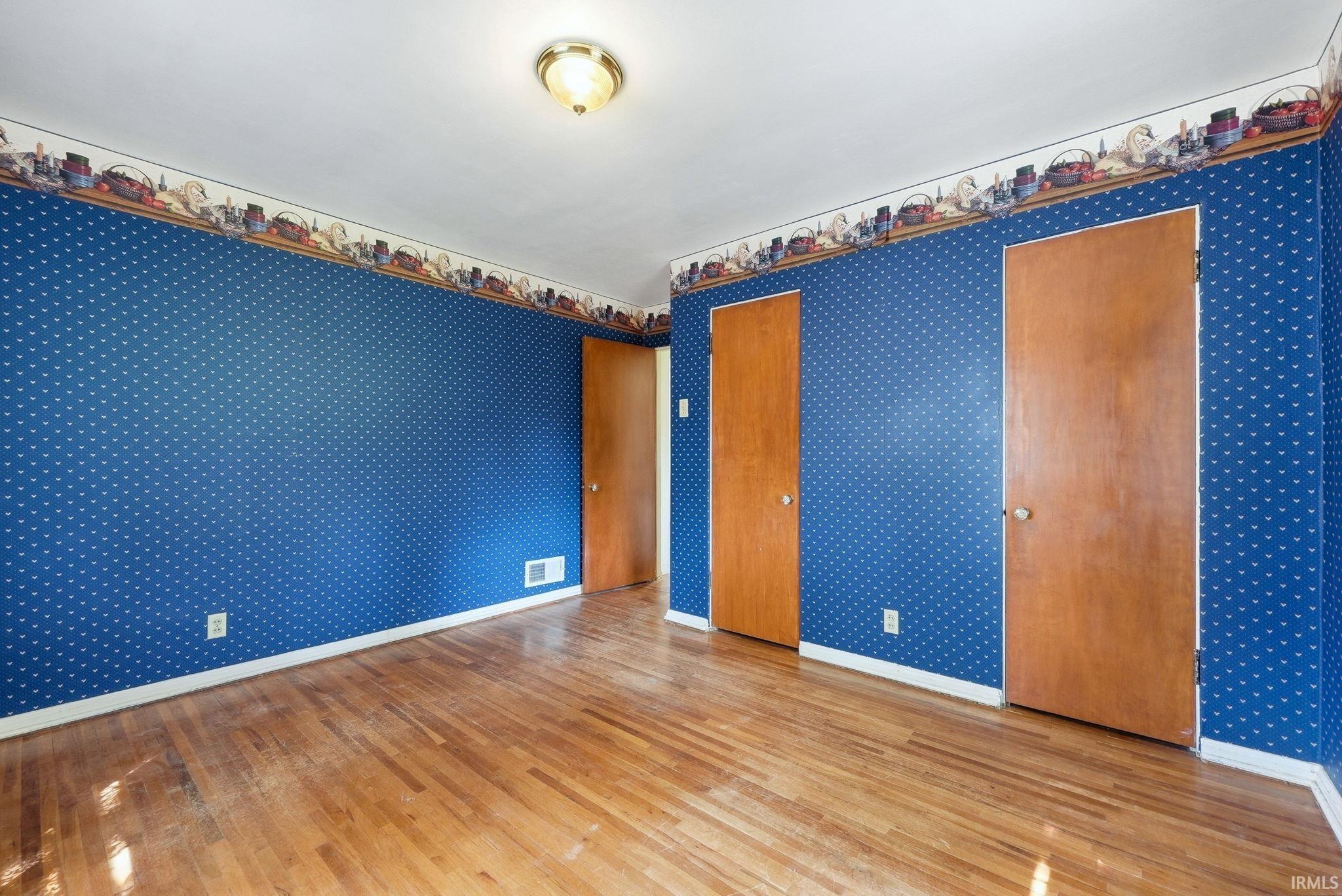 Hardwood flooring complementing blue patterned wallpaper and white trim