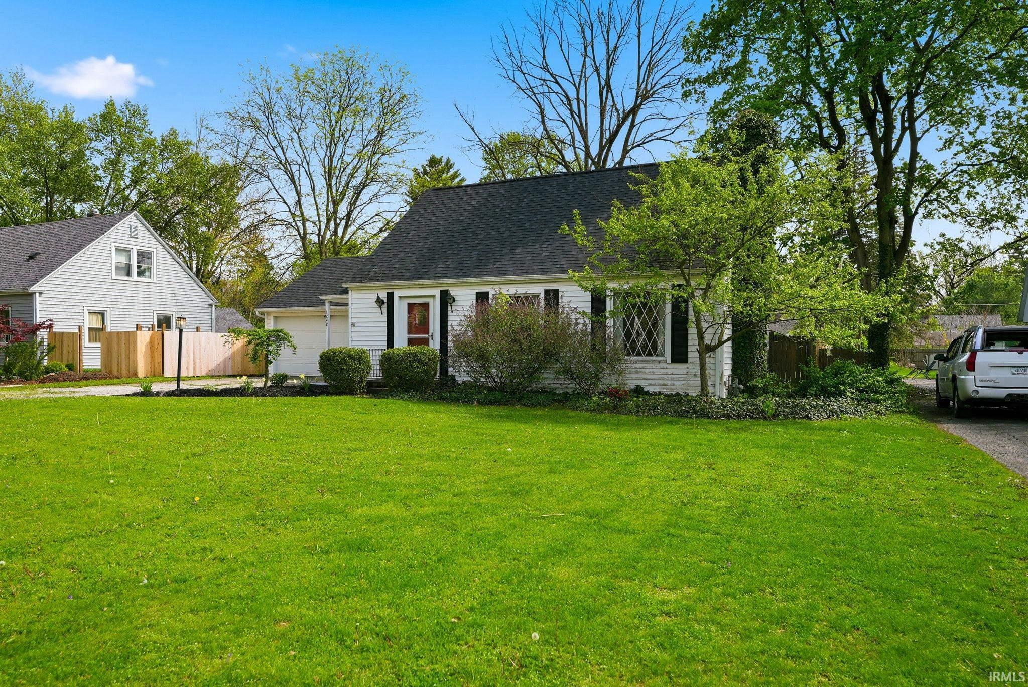White siding residence with a dark shingle roof, featuring a single-car garage and a black-trimmed front door